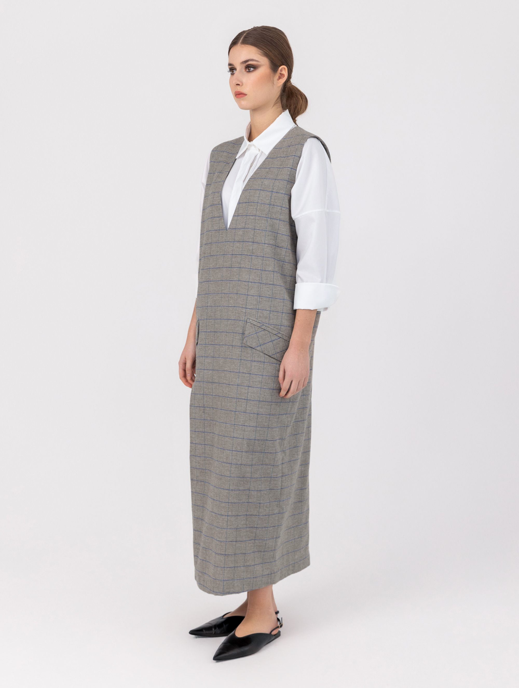 Ärmelloses, locker geschnittenes Kleid mit tiefem V-Ausschnitt und Pattentaschen sowie einem langen Seitenschlitz auf der Vorderseite. Hergestellt aus nachhaltigen Fasern.