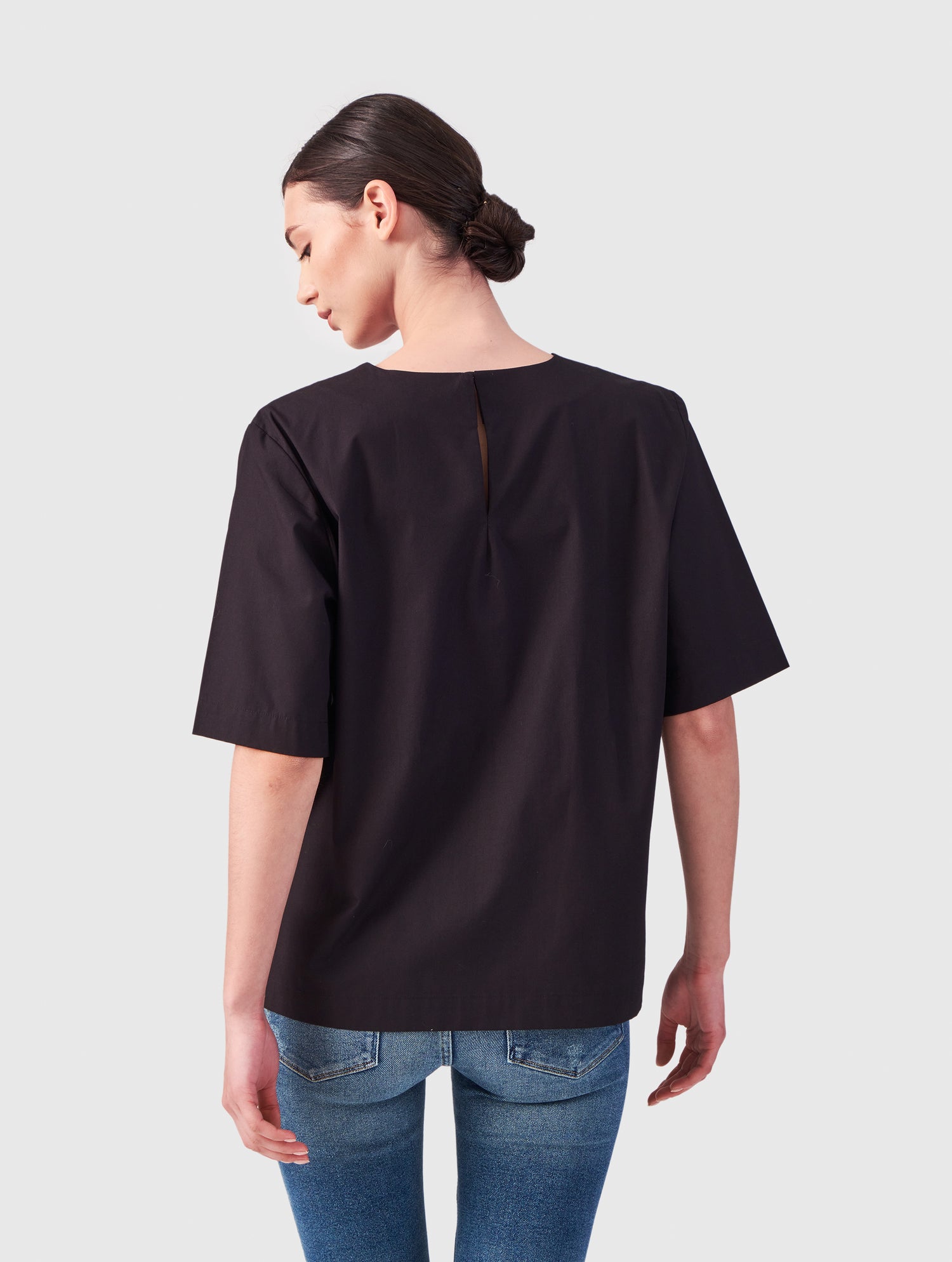 Hochgeschlossene Bluse aus Baumwolle im T-Shirt-Stil mit Knopfverschluss auf der Rückseite.