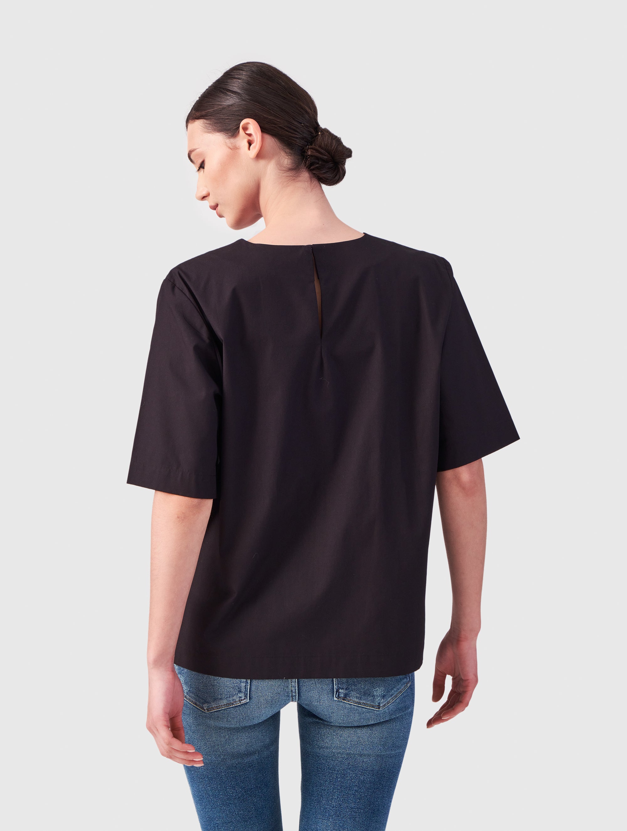 Hochgeschlossene Bluse aus Baumwolle im T-Shirt-Stil mit Knopfverschluss auf der Rückseite.
