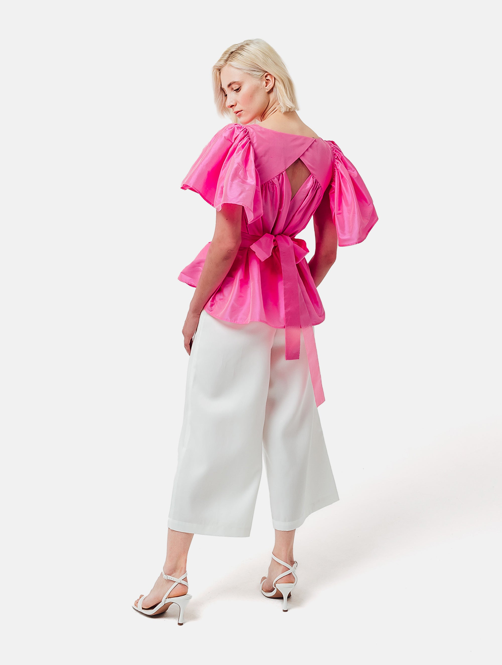 Weit geschnittene Bluse mit breitem Volantärmel und raffiniertem Rückenausschnitt aus pinken Dupionsilk, sowie versteckten Taschen in der Seitennaht. Zusätzlich mit breiten Gürtel zum Binden tragbar. Dieses Produkt ist Teil unserer Reborn Linie.