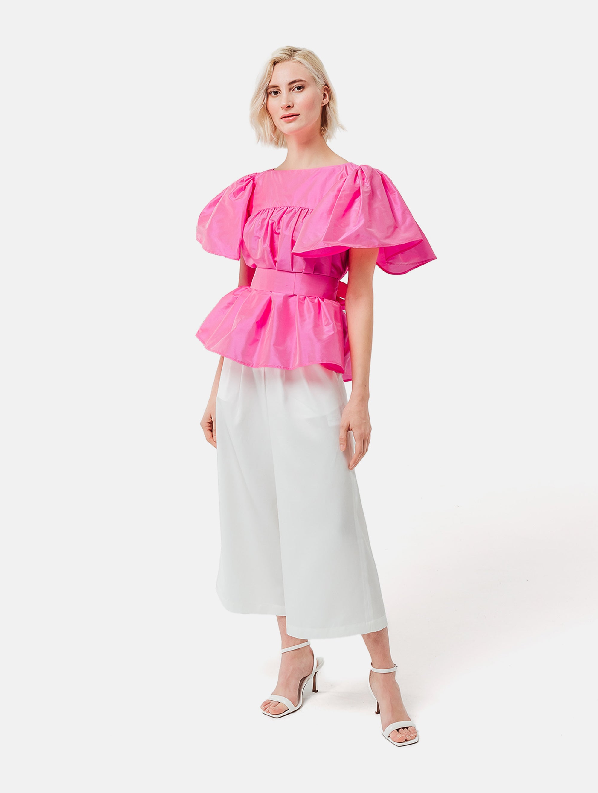 Weit geschnittene Bluse mit breitem Volantärmel und raffiniertem Rückenausschnitt aus pinken Dupionsilk, sowie versteckten Taschen in der Seitennaht. Zusätzlich mit breiten Gürtel zum Binden tragbar. Dieses Produkt ist Teil unserer Reborn Linie.