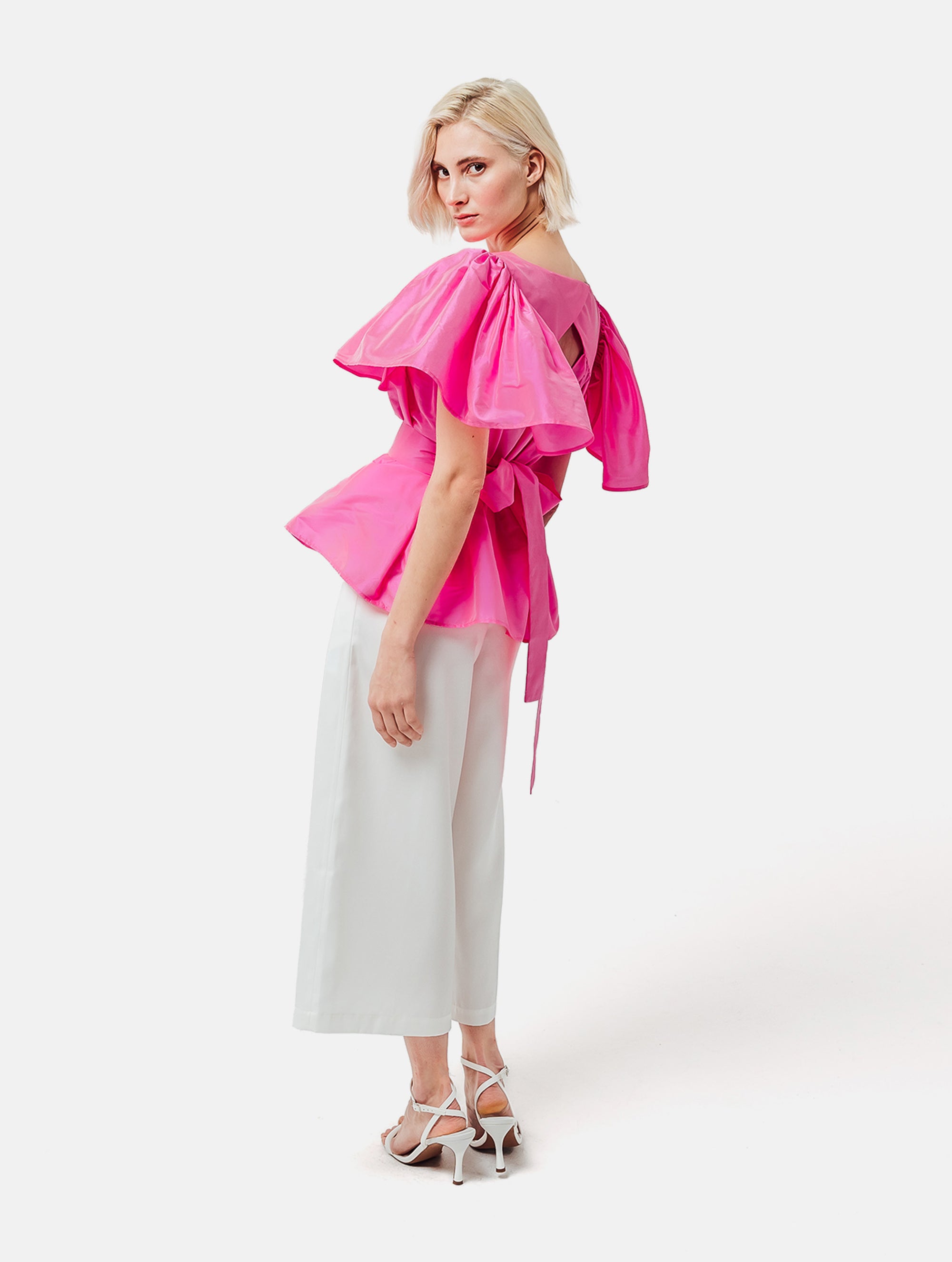 Weit geschnittene Bluse mit breitem Volantärmel und raffiniertem Rückenausschnitt aus pinken Dupionsilk, sowie versteckten Taschen in der Seitennaht. Zusätzlich mit breiten Gürtel zum Binden tragbar. Dieses Produkt ist Teil unserer Reborn Linie.
