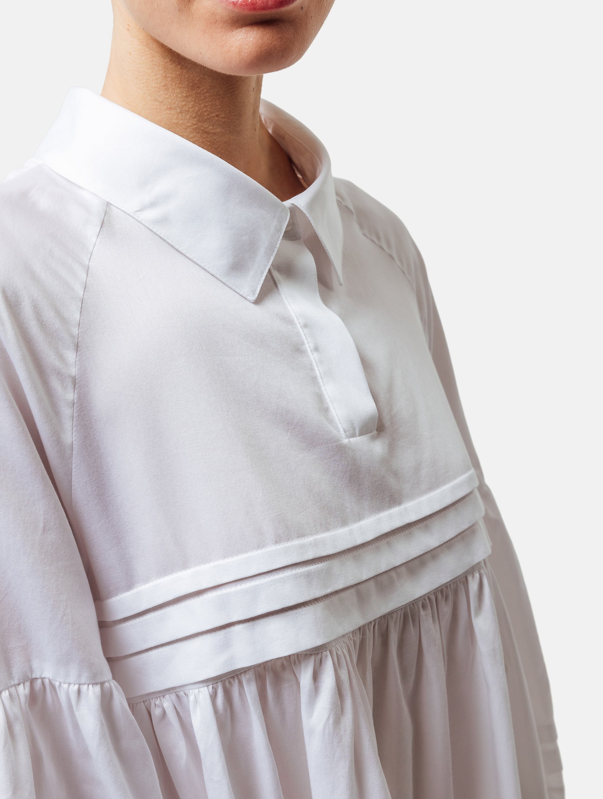 Weites Hemdkragenkleid mit weiten Laternenärmeln, Biesen an der Brust, Ärmeln, aufgesetzenTaschen und Saumende, sowie verdeckter Knopfleiste. Gefertigt aus Premiumbaumwolle mit Satin-Touch.