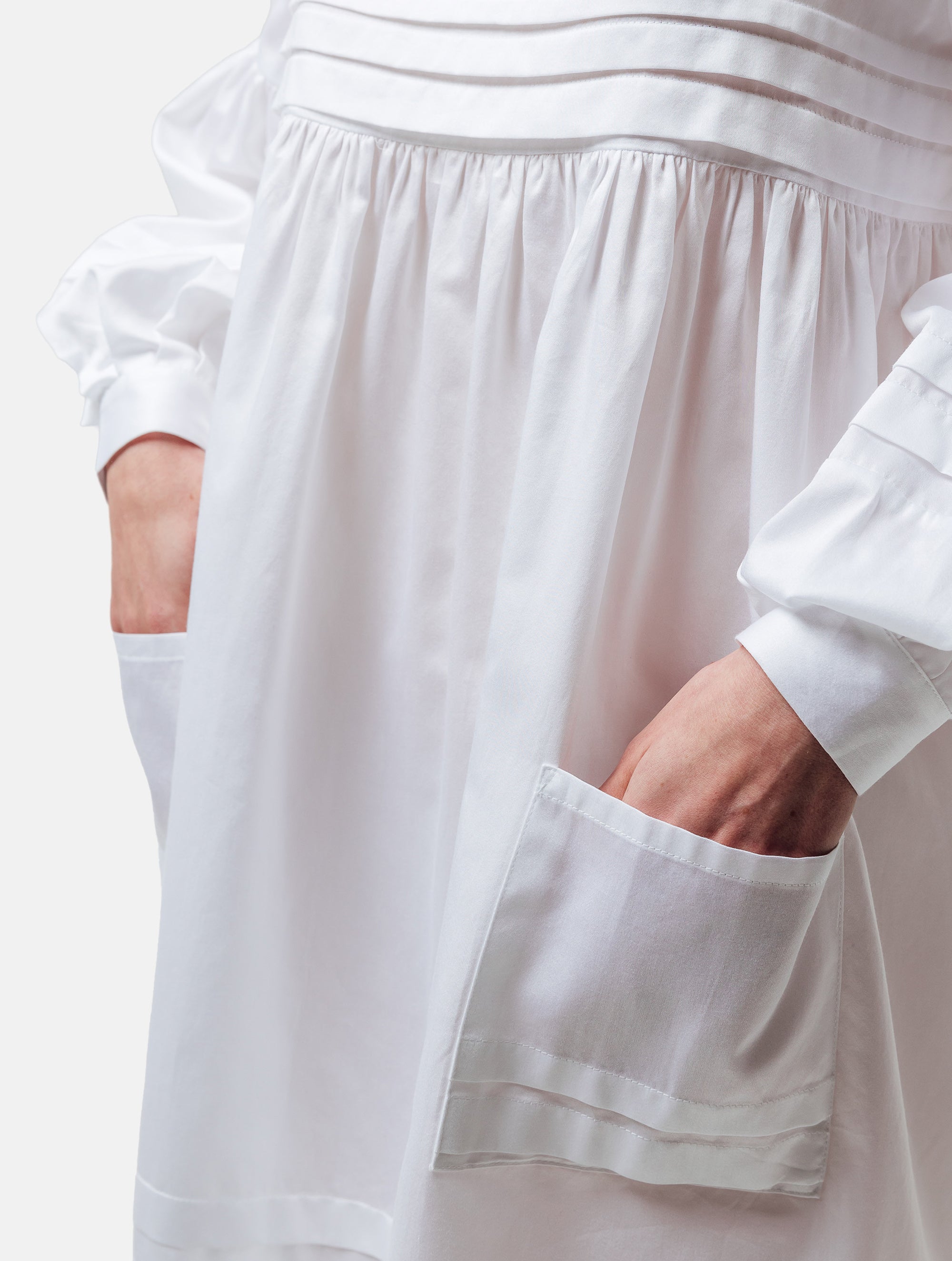 Weites Hemdkragenkleid mit weiten Laternenärmeln, Biesen an der Brust, Ärmeln, aufgesetzenTaschen und Saumende, sowie verdeckter Knopfleiste. Gefertigt aus Premiumbaumwolle mit Satin-Touch.
