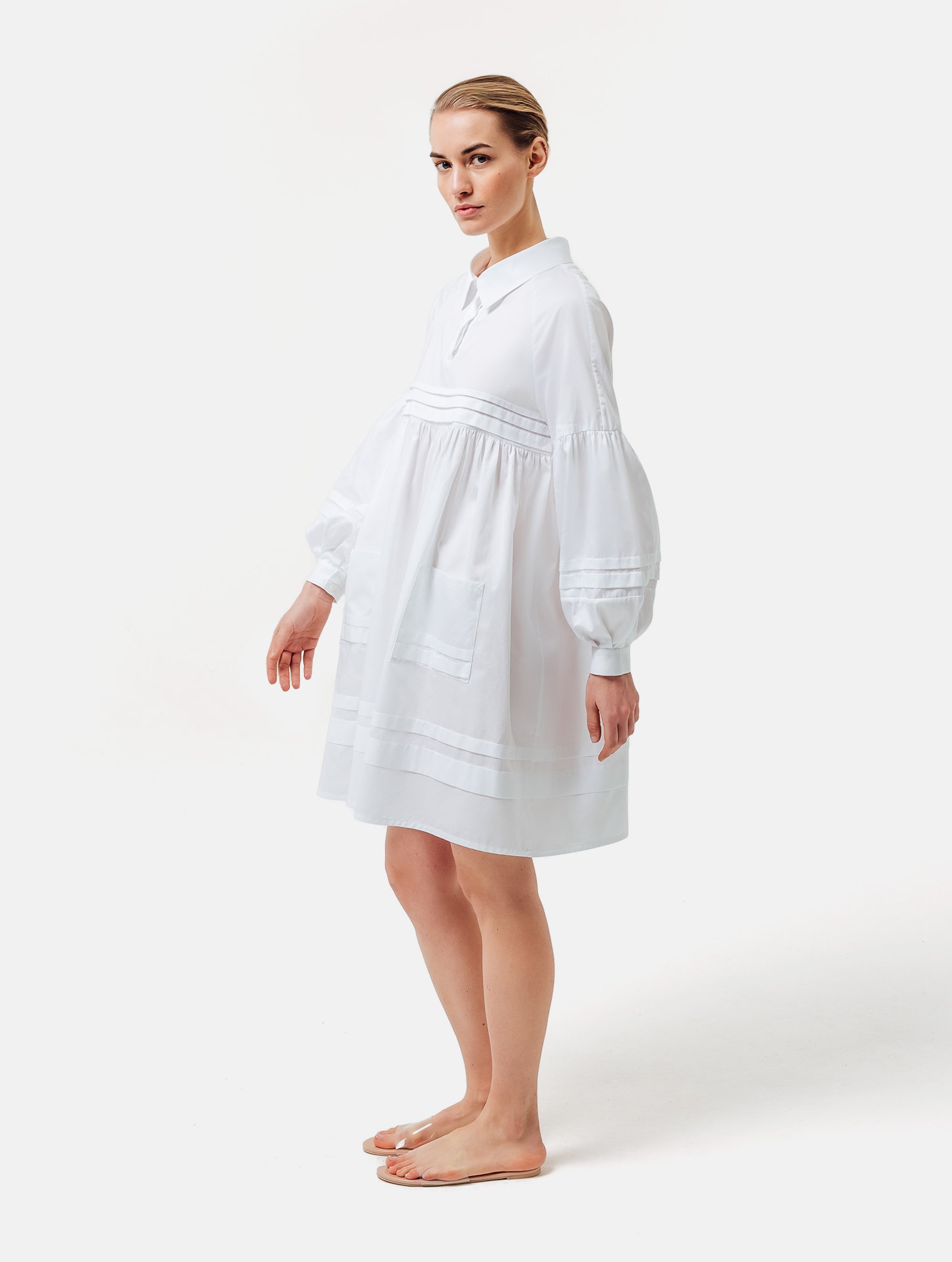 Weites Hemdkragenkleid mit weiten Laternenärmeln, Biesen an der Brust, Ärmeln, aufgesetzenTaschen und Saumende, sowie verdeckter Knopfleiste. Gefertigt aus Premiumbaumwolle mit Satin-Touch.