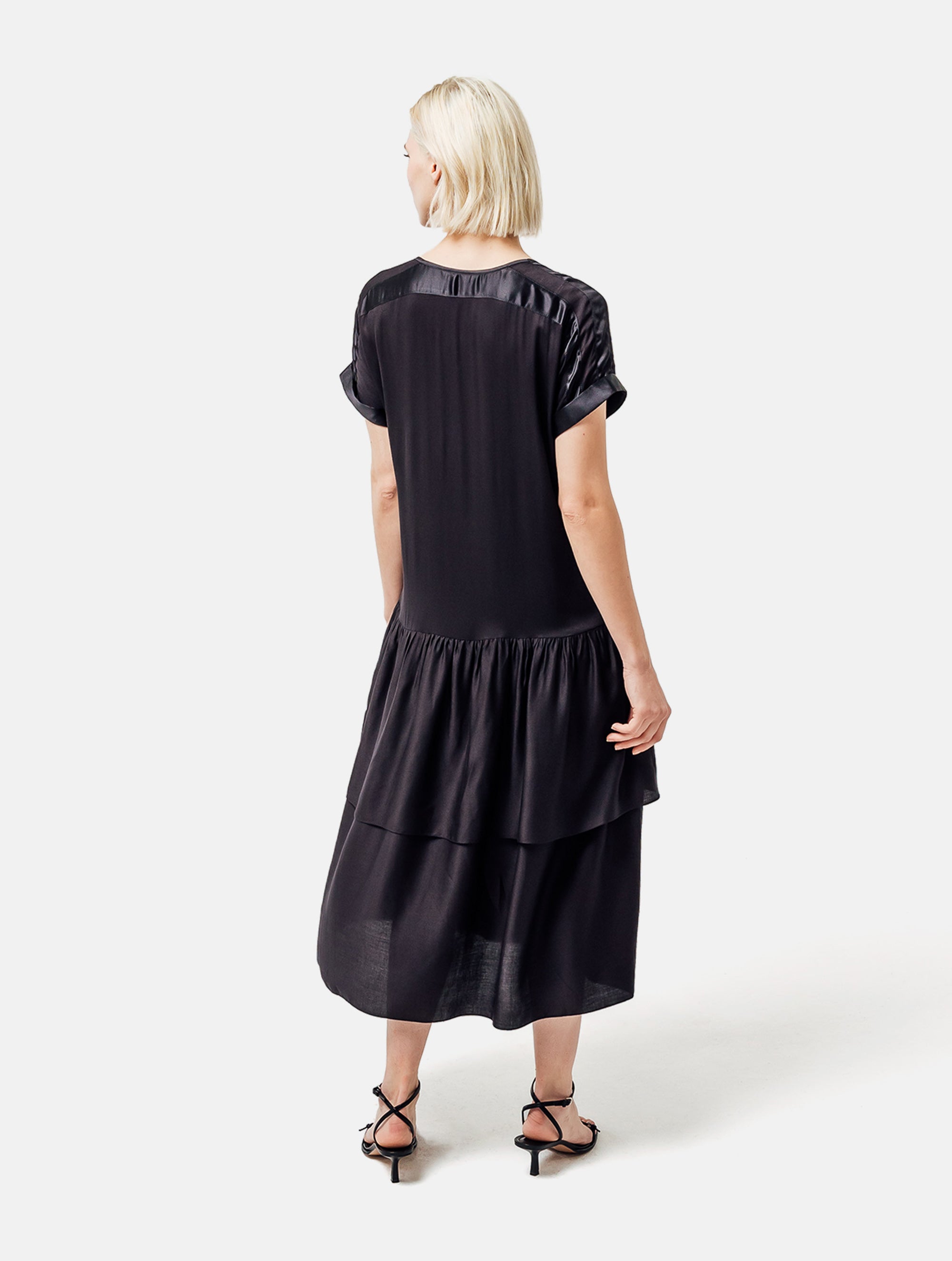 Locker fallendes Kurzarmkleid mit V-Ausschnitt und Volantrock aus Seidensatin und Viskose. Dieses Produkt ist Teil unserer Reborn Linie.