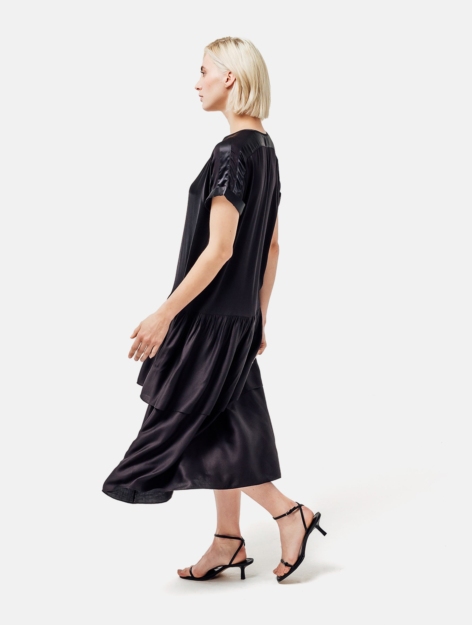 Locker fallendes Kurzarmkleid mit V-Ausschnitt und Volantrock aus Seidensatin und Viskose. Dieses Produkt ist Teil unserer Reborn Linie.