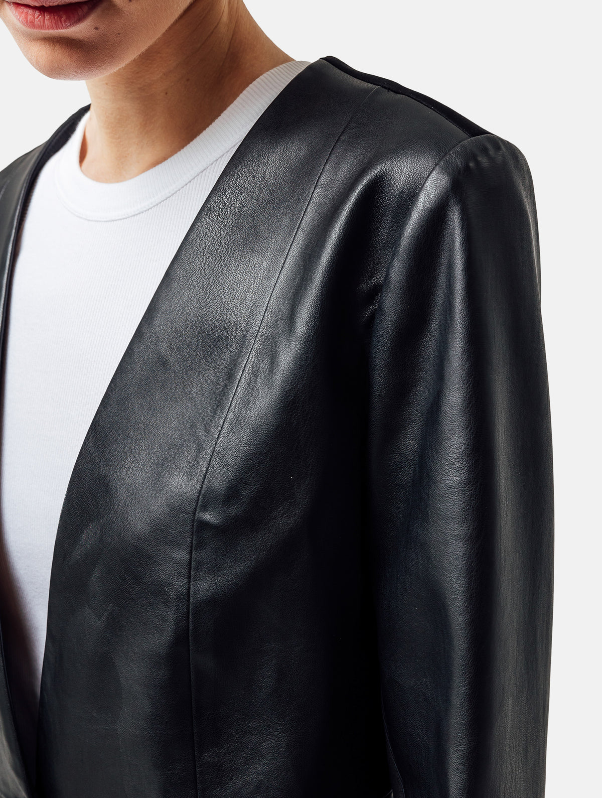 Einknöpfiger, taillierter Zwei-Komponenten Kurzblazer aus veganem Leder im Vorderteil und Scuba-Jersey im Rückteil, sowie schmalen Arm. Dieses Modell ist Teil unserer REBORN-Linie und steht für unsere "Zero-Waste-Politik", da mit Stoff aus Altbestand gefertigt.