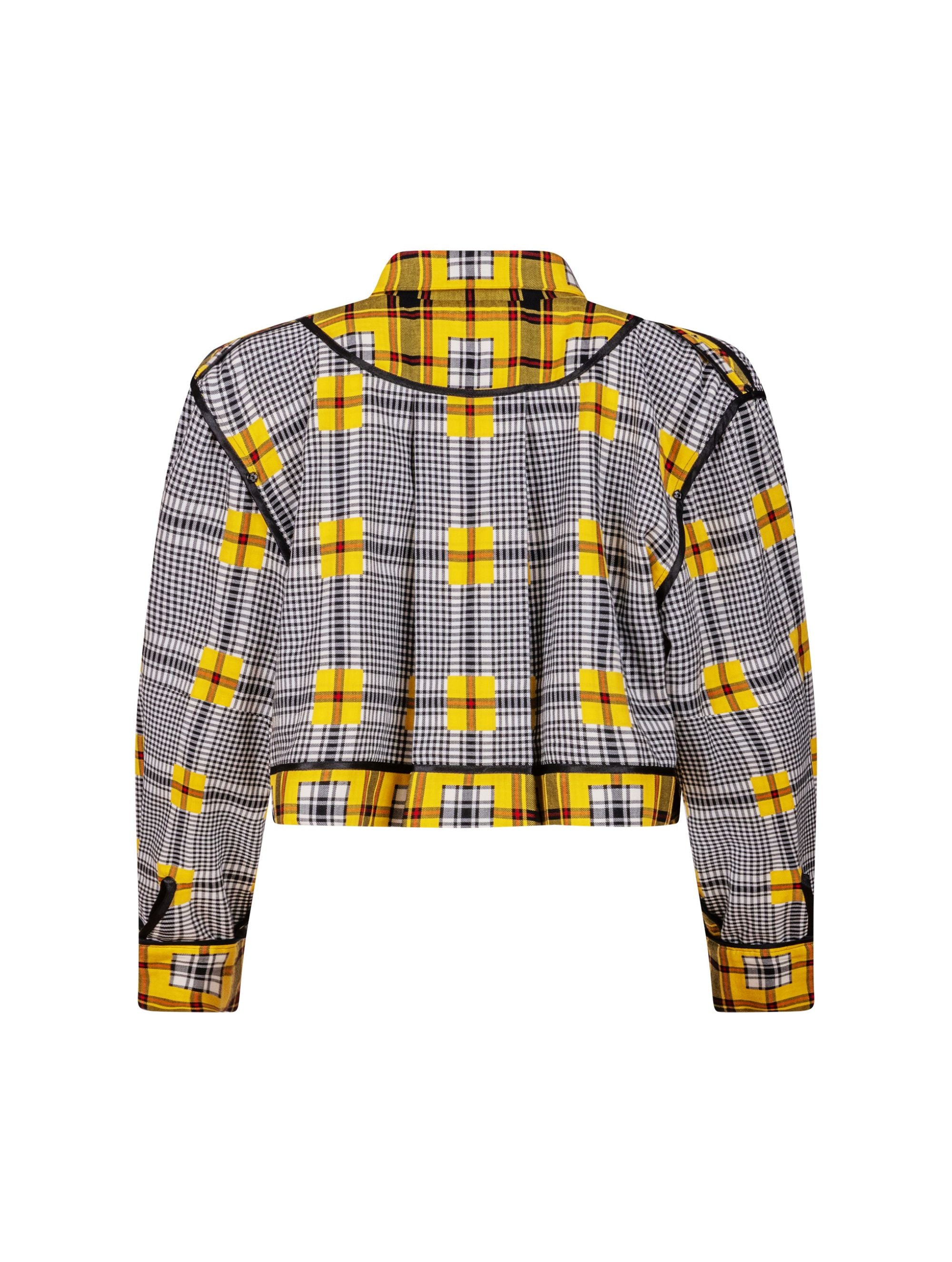 Doppelseitige Karo-Kurzjacke mit abnehmbaren Schulterpolstern, eingesetzten Ärmeln mit Ärmelgürteln und Schulterklappen sowie vorderen Halbpasse. Die Jacke kann von beiden Seiten getragen werden. Hergestellt aus Naturfasern.