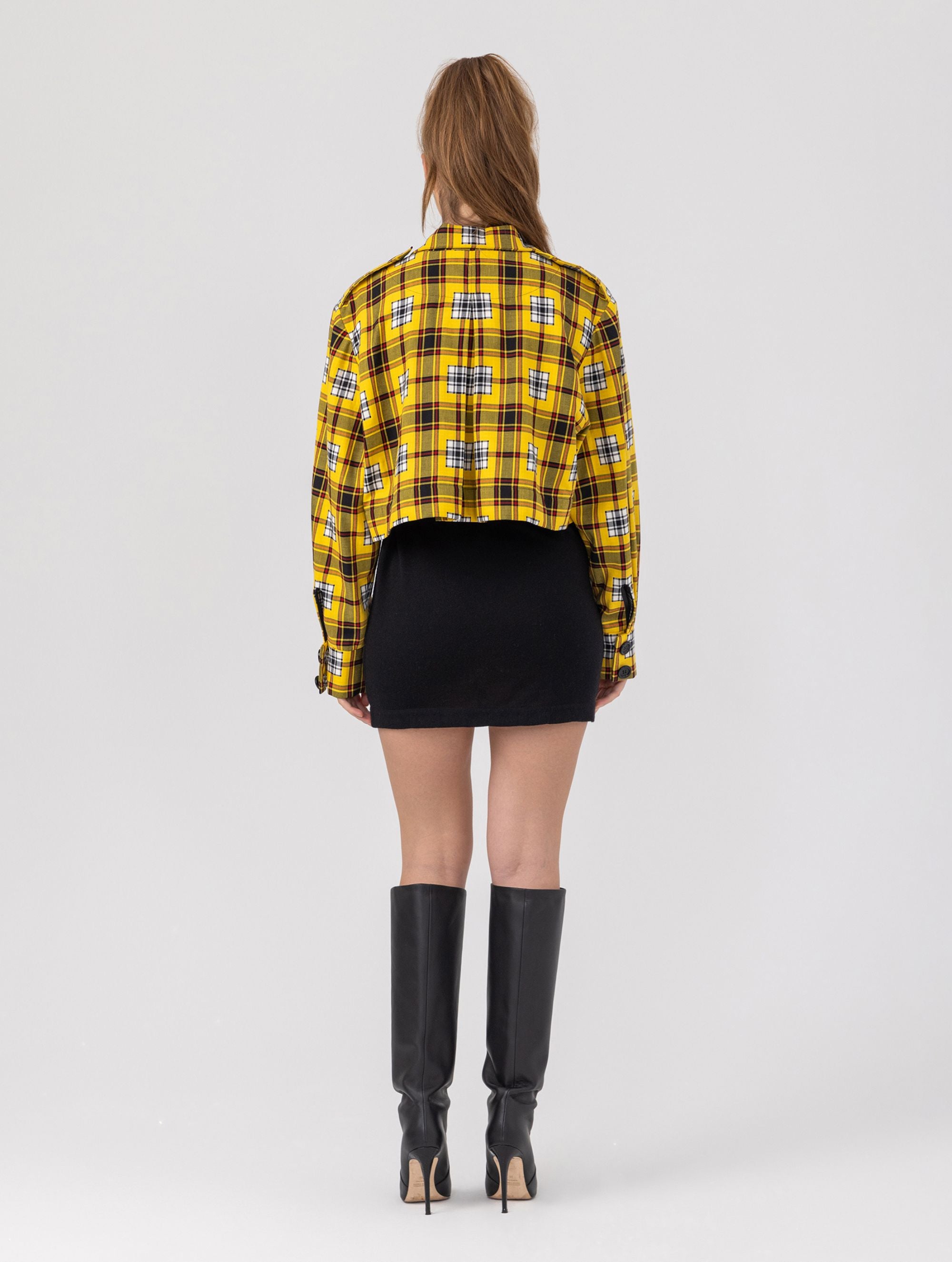 Doppelseitige Karo-Kurzjacke mit abnehmbaren Schulterpolstern, eingesetzten Ärmeln mit Ärmelgürteln und Schulterklappen sowie vorderen Halbpasse. Die Jacke kann von beiden Seiten getragen werden. Hergestellt aus Naturfasern.