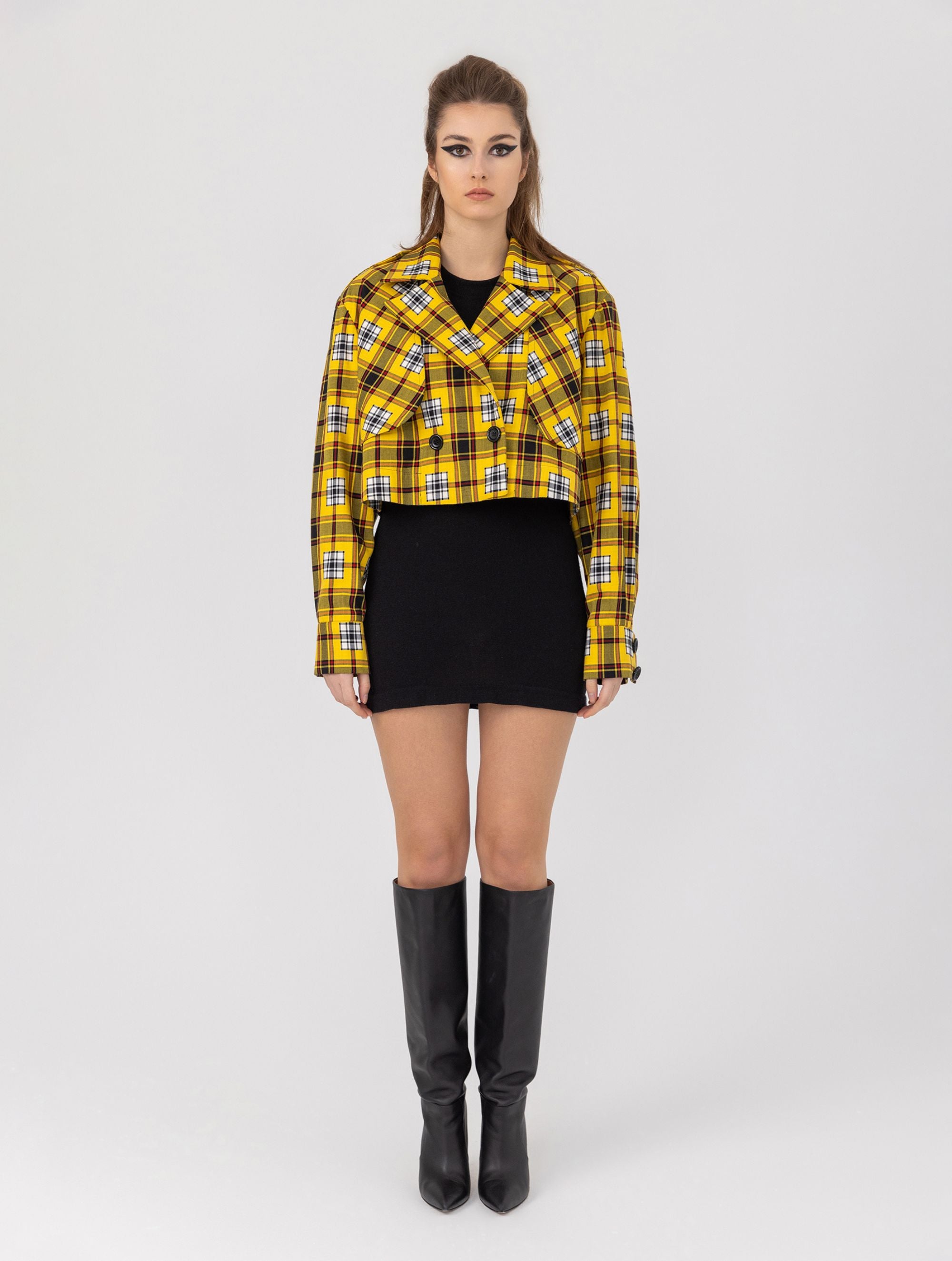 Doppelseitige Karo-Kurzjacke mit abnehmbaren Schulterpolstern, eingesetzten Ärmeln mit Ärmelgürteln und Schulterklappen sowie vorderen Halbpasse. Die Jacke kann von beiden Seiten getragen werden. Hergestellt aus Naturfasern.