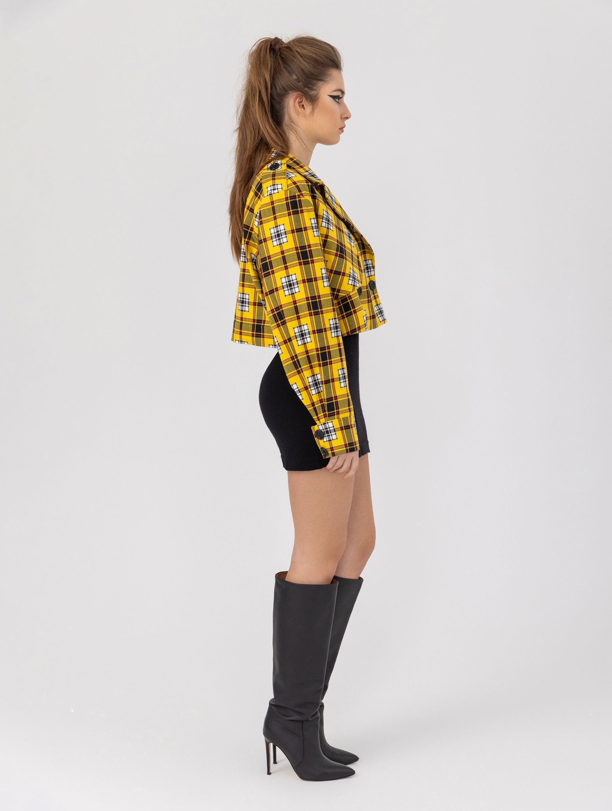 Doppelseitige Karo-Kurzjacke mit abnehmbaren Schulterpolstern, eingesetzten Ärmeln mit Ärmelgürteln und Schulterklappen sowie vorderen Halbpasse. Die Jacke kann von beiden Seiten getragen werden. Hergestellt aus Naturfasern.