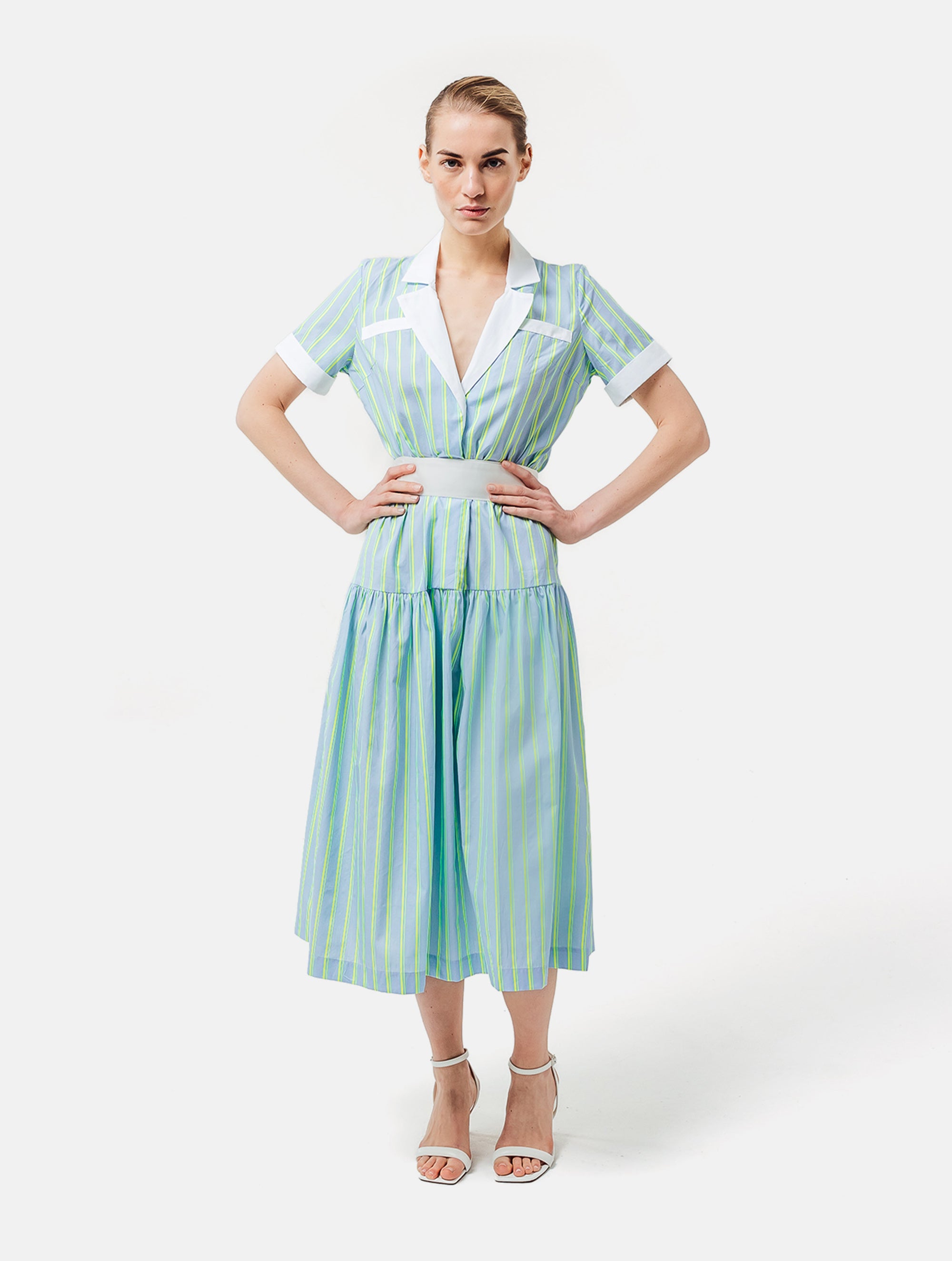 Gestreiftes Midikleid mit weiß abgesetzten Reverskragen, sowie Ärmelenden, raffiniertem Rückenausschnitt, verdeckter Knopfleiste, tragbar mit und ohne Gürtel aus weißer Baumwolle. Stoffe kommen aus dem Altbestand der Firma, daher nachhaltig.