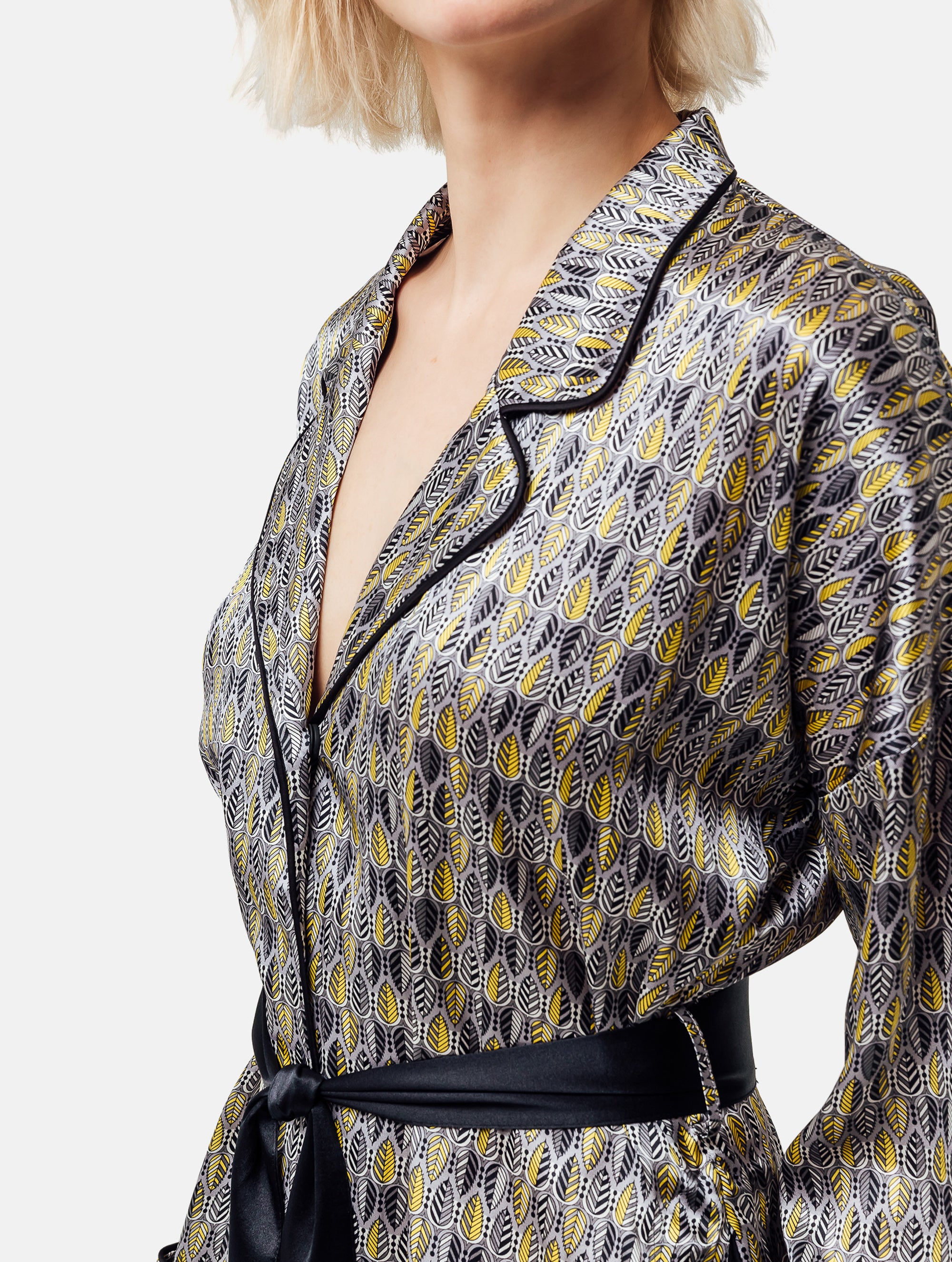 Bedruckte Oversize Seidensatin-Blusenjacke im Pyjama-Stil mit schmalem Revers und Seitenschlitzen sowie schwarzen Paspeln und Seidensatin-Gürtel. Hergestellt aus Naturfaser.