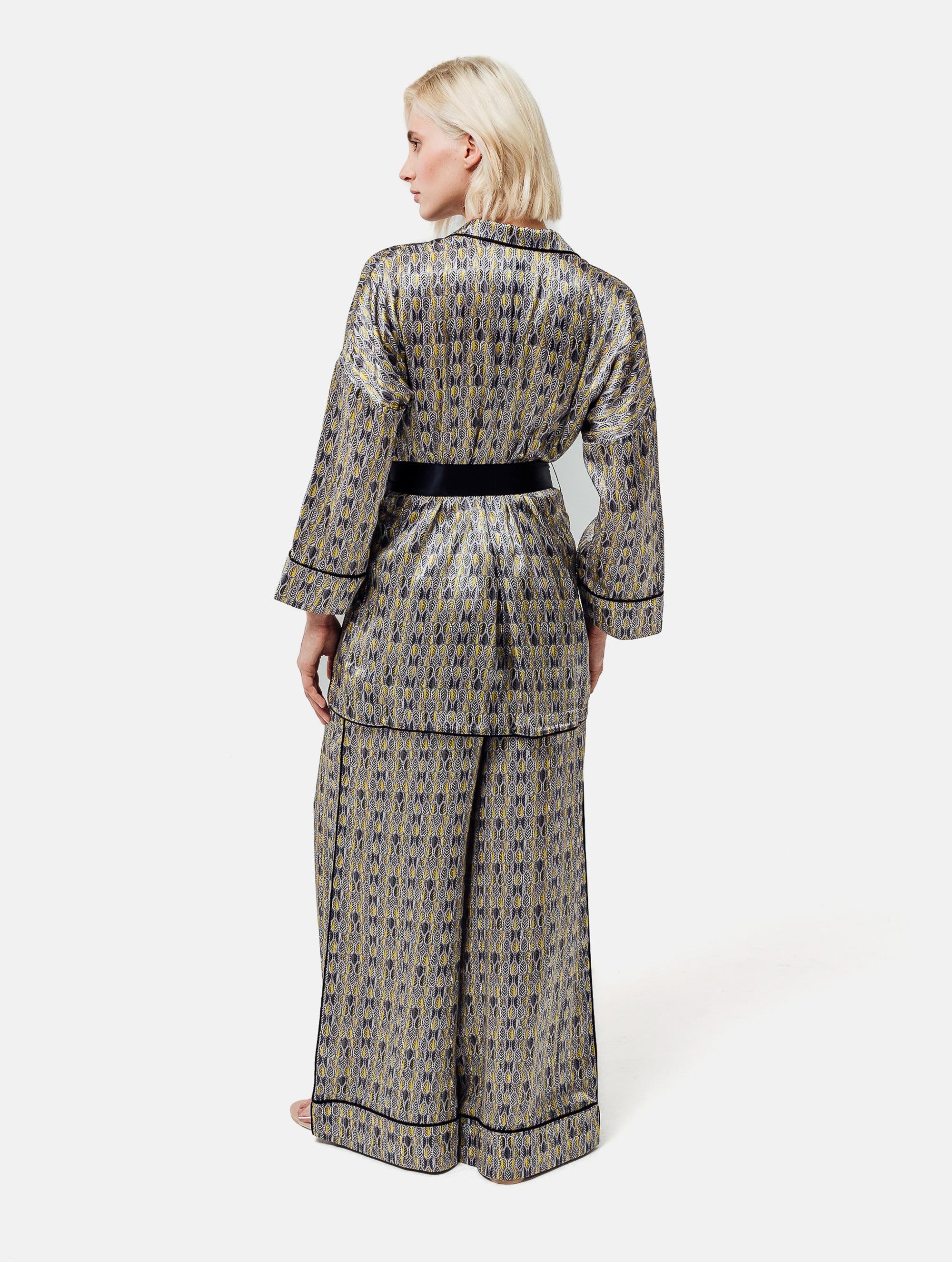 Bedruckte Oversize Seidensatin-Blusenjacke im Pyjama-Stil mit schmalem Revers und Seitenschlitzen sowie schwarzen Paspeln und Seidensatin-Gürtel. Hergestellt aus Naturfaser.