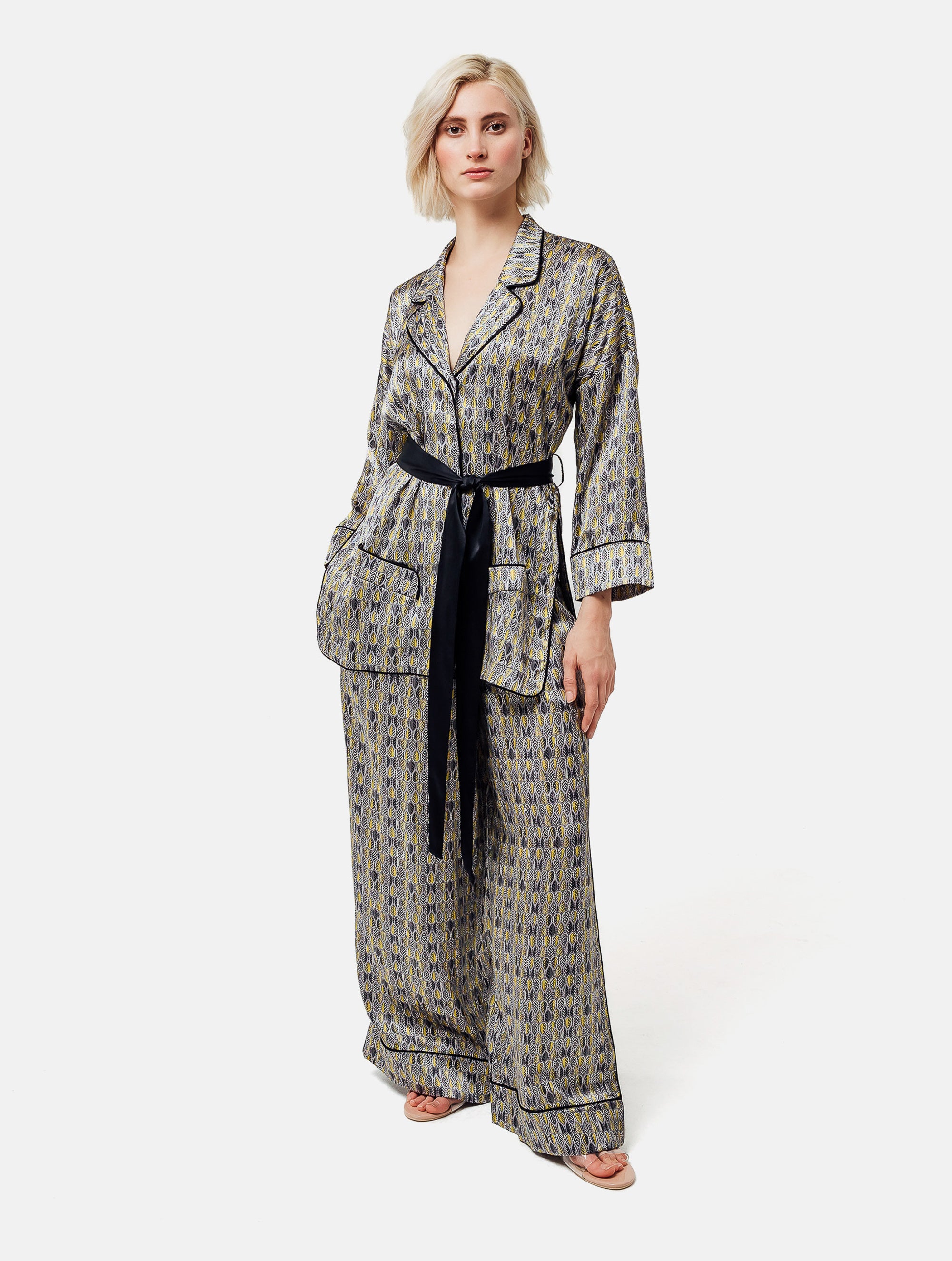 Bedruckte Oversize Seidensatin-Blusenjacke im Pyjama-Stil mit schmalem Revers und Seitenschlitzen sowie schwarzen Paspeln und Seidensatin-Gürtel. Hergestellt aus Naturfaser.