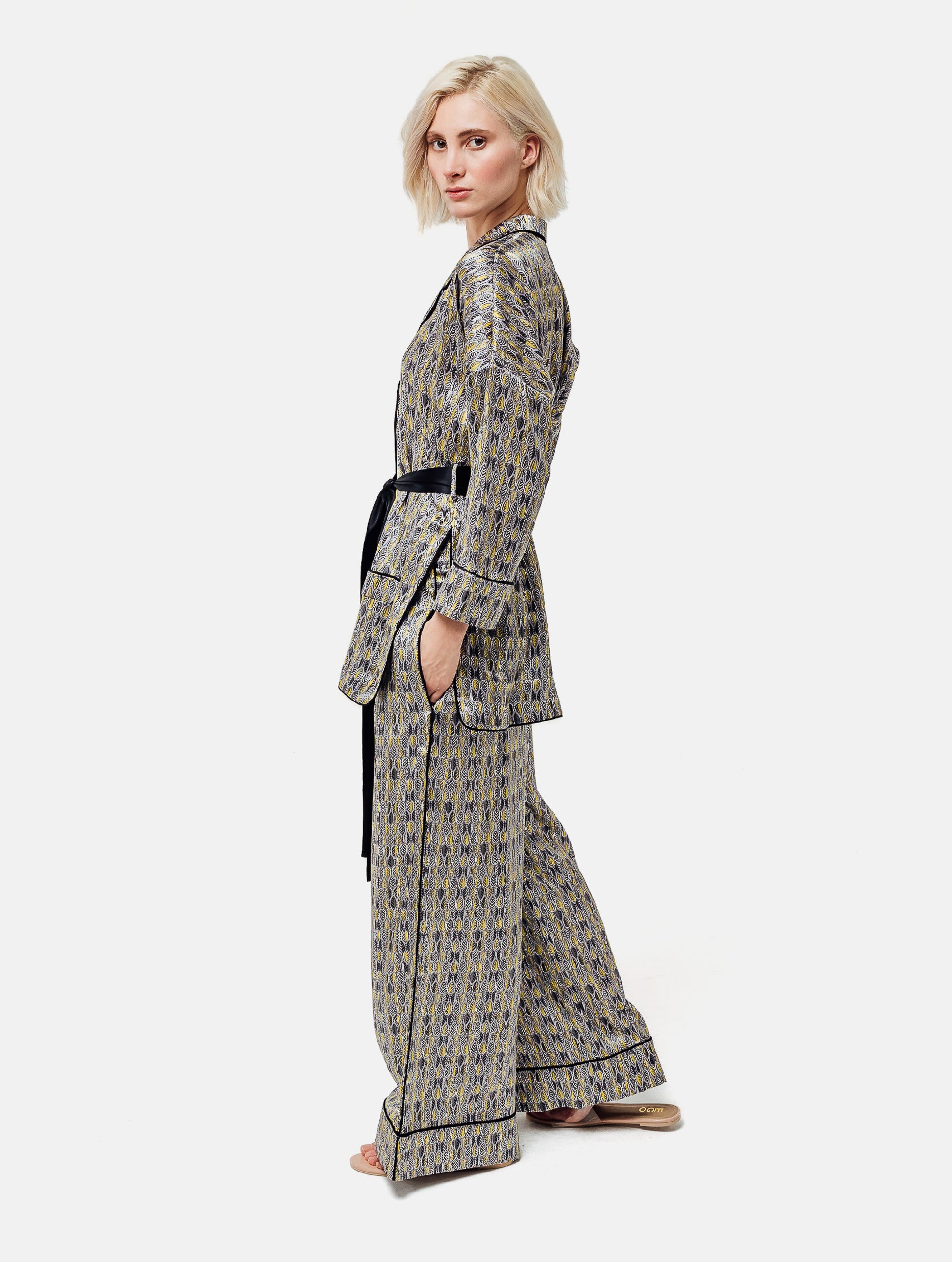 Bedruckte Oversize Seidensatin-Blusenjacke im Pyjama-Stil mit schmalem Revers und Seitenschlitzen sowie schwarzen Paspeln und Seidensatin-Gürtel. Hergestellt aus Naturfaser.