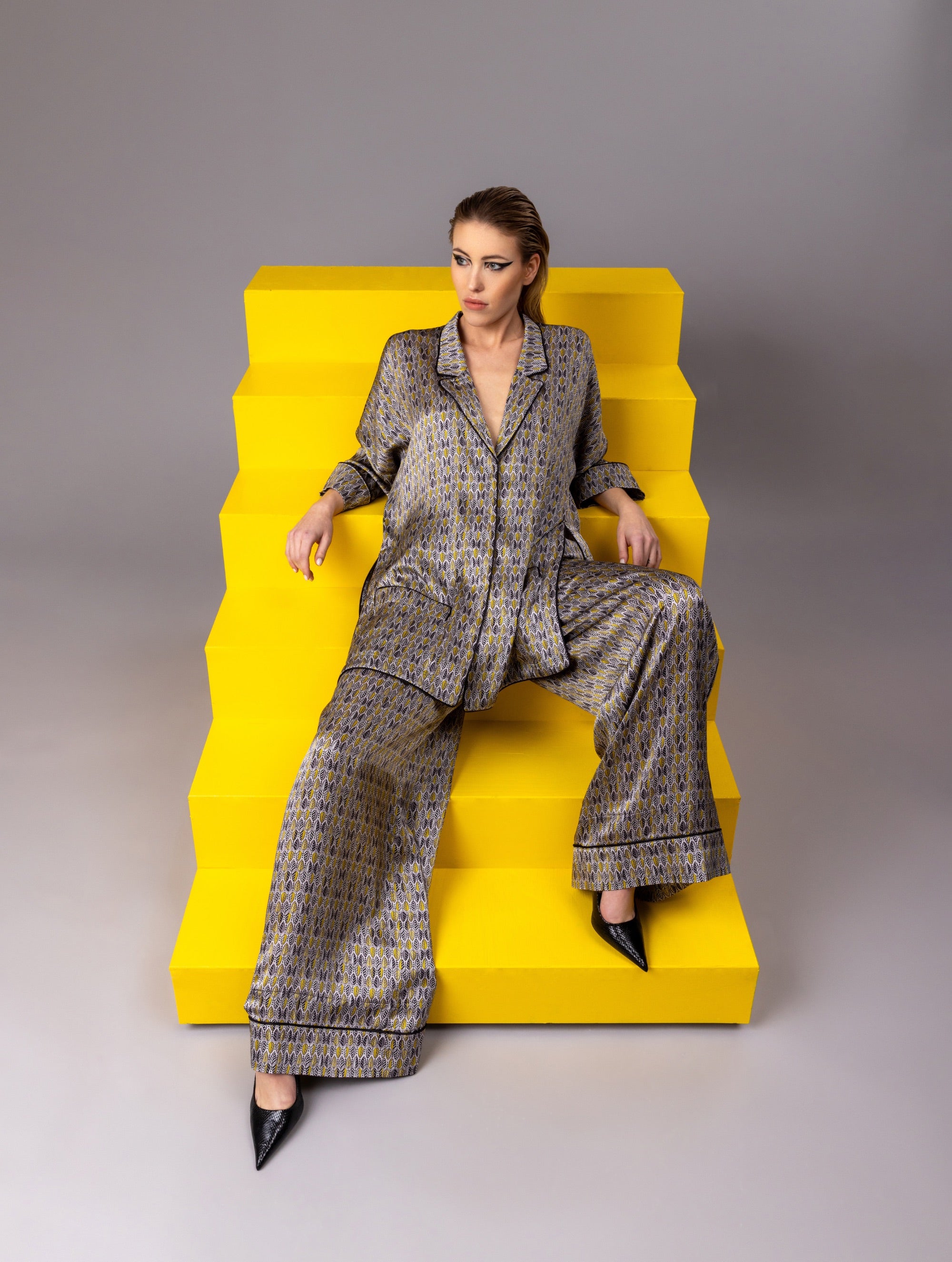 Bedruckte Oversize Seidensatin-Blusenjacke im Pyjama-Stil mit schmalem Revers und Seitenschlitzen sowie schwarzen Paspeln und Seidensatin-Gürtel. Hergestellt aus Naturfaser.