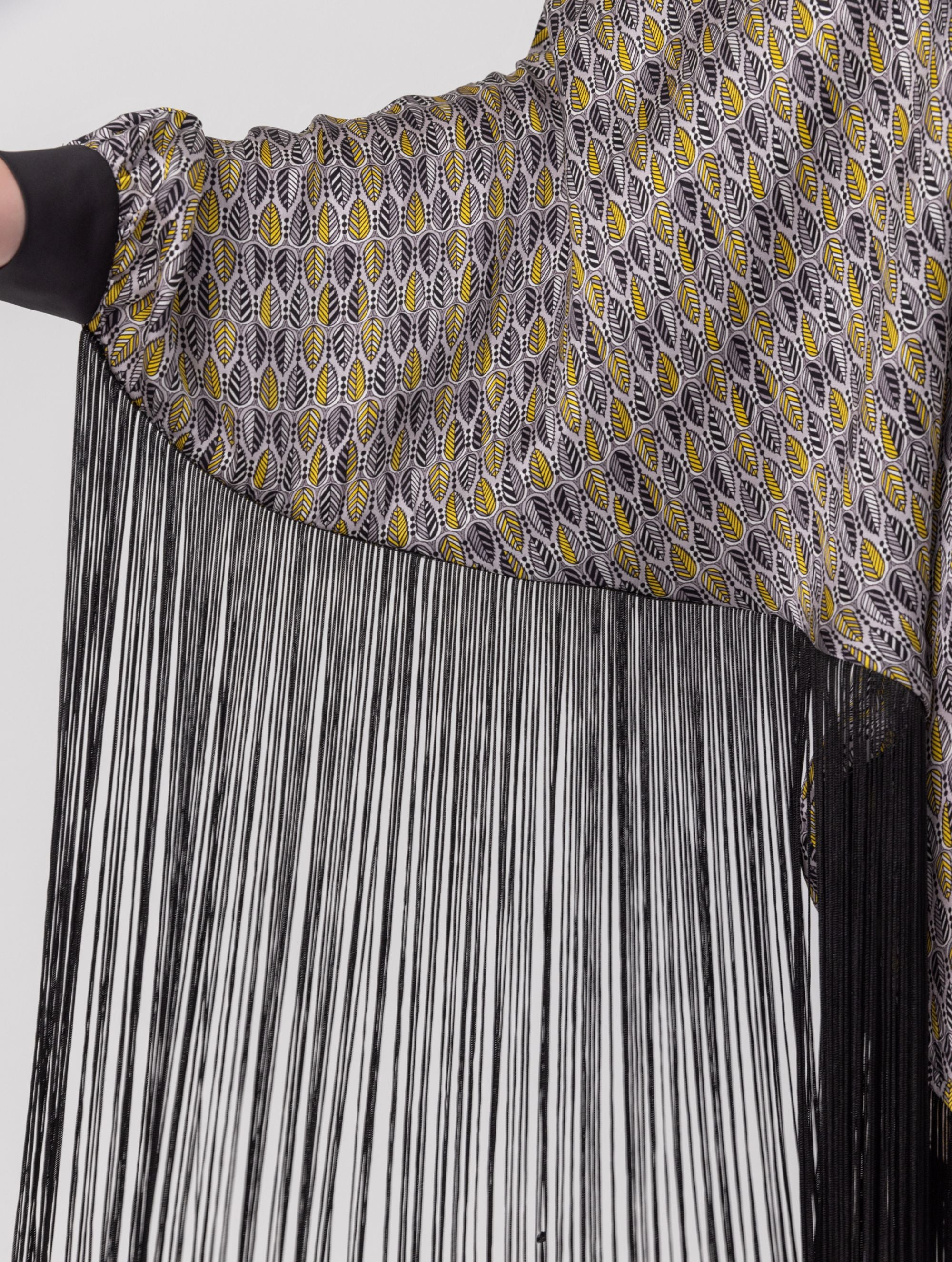 Bedrucktes Seidenponcho-Kleid mit langen Fransen aus schwarzer Viskose und schwarzen Seidensatin-Details an Kragen und Manschetten. Hergestellt aus Naturfaser.