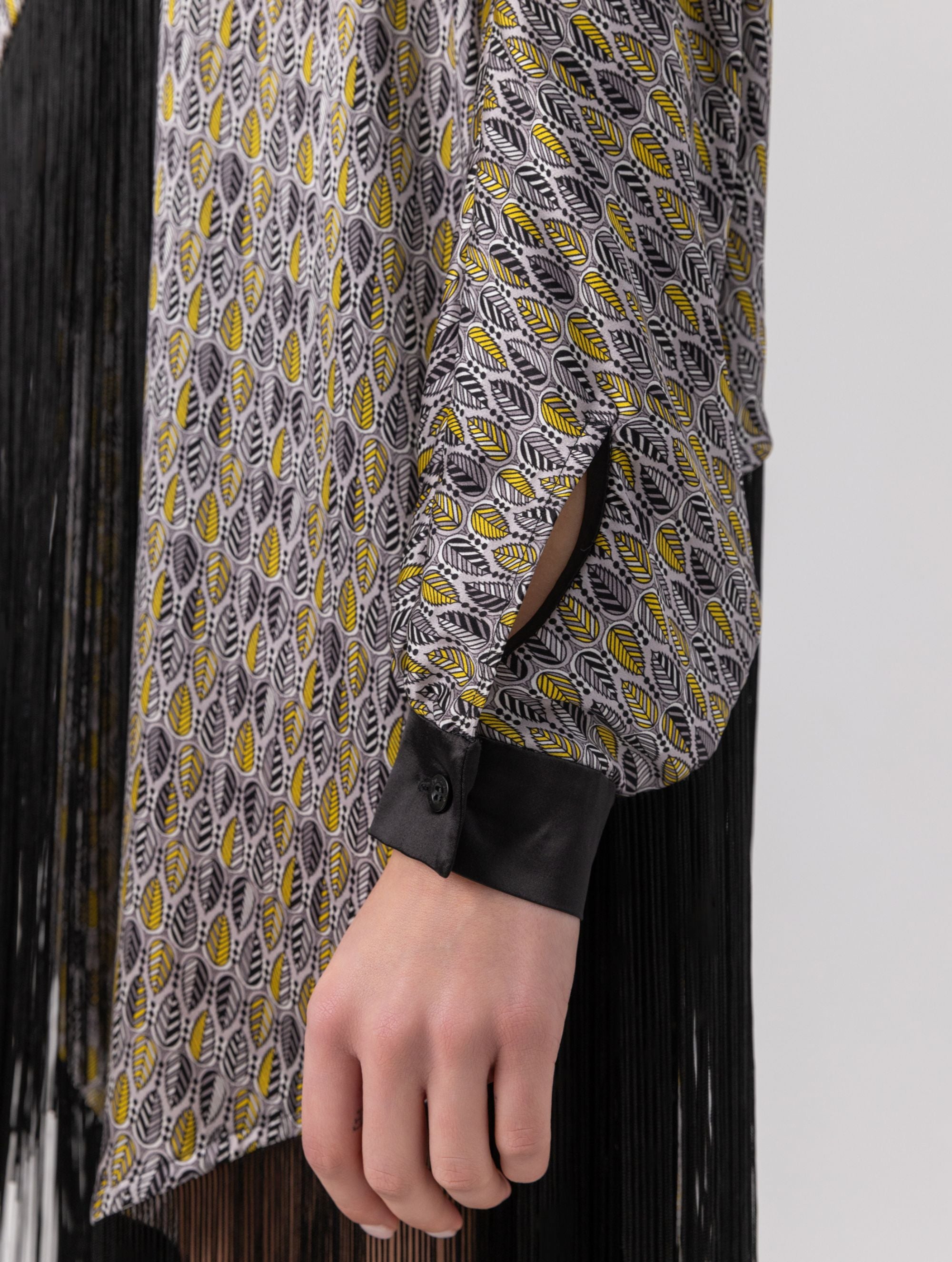 Bedrucktes Seidenponcho-Kleid mit langen Fransen aus schwarzer Viskose und schwarzen Seidensatin-Details an Kragen und Manschetten. Hergestellt aus Naturfaser.