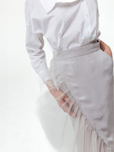 Figurbetonter knielanger Wickelrock mit doppelgelegtem breiten Volant aus Tüll und Bändern zum Binden in der Taille. Dieses Modell ist Teil unserer Reborn Linie, da es aus dem ehemaligen Rock Berta hergestellt worden ist.