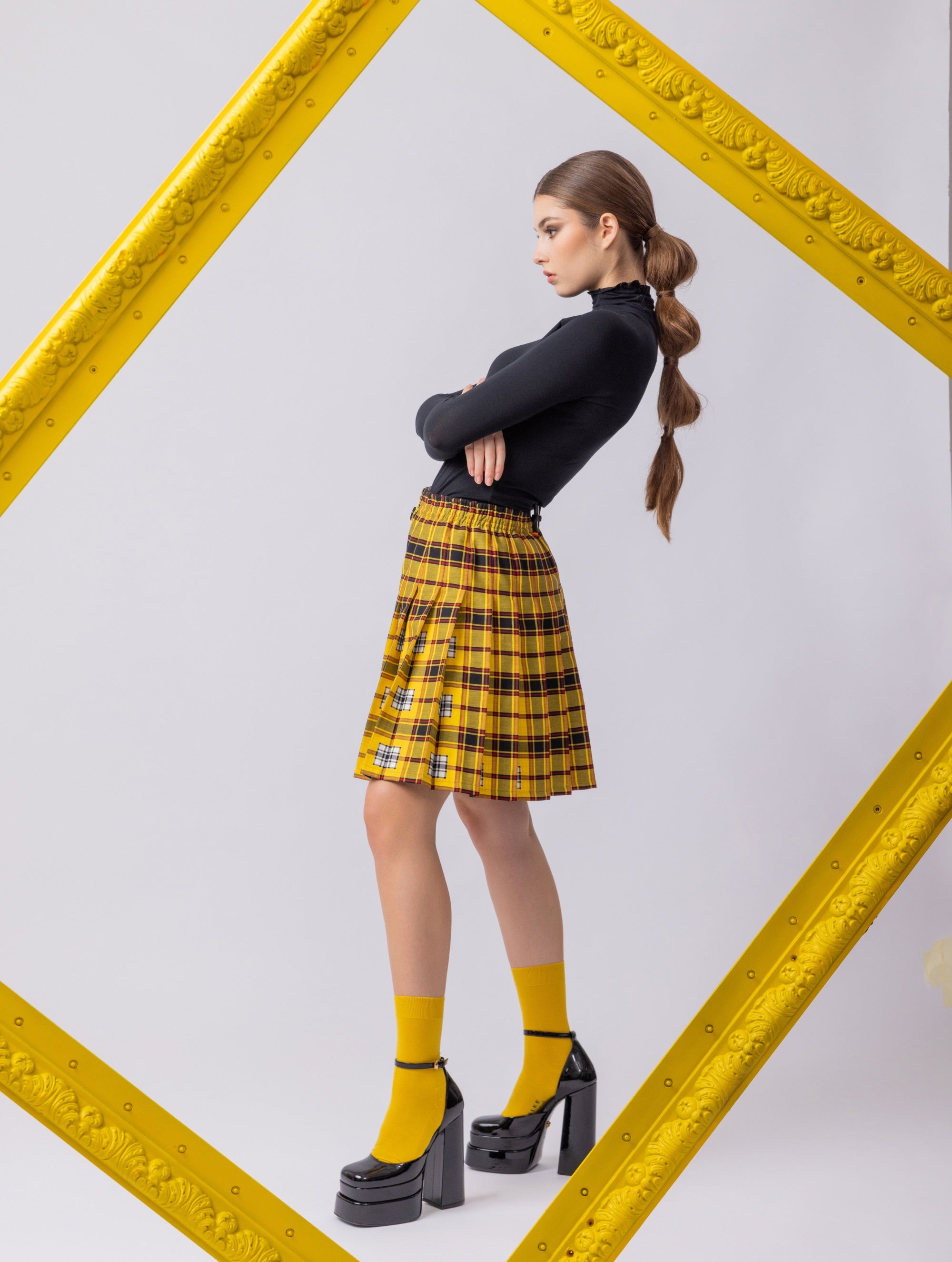 Doppelseitig karierter Faltenminirock mit elastischem Bund und Knopfleiste auf der Vorderseite. Der Rock kann von beiden Seiten getragen werden. Hergestellt aus Naturfasern.