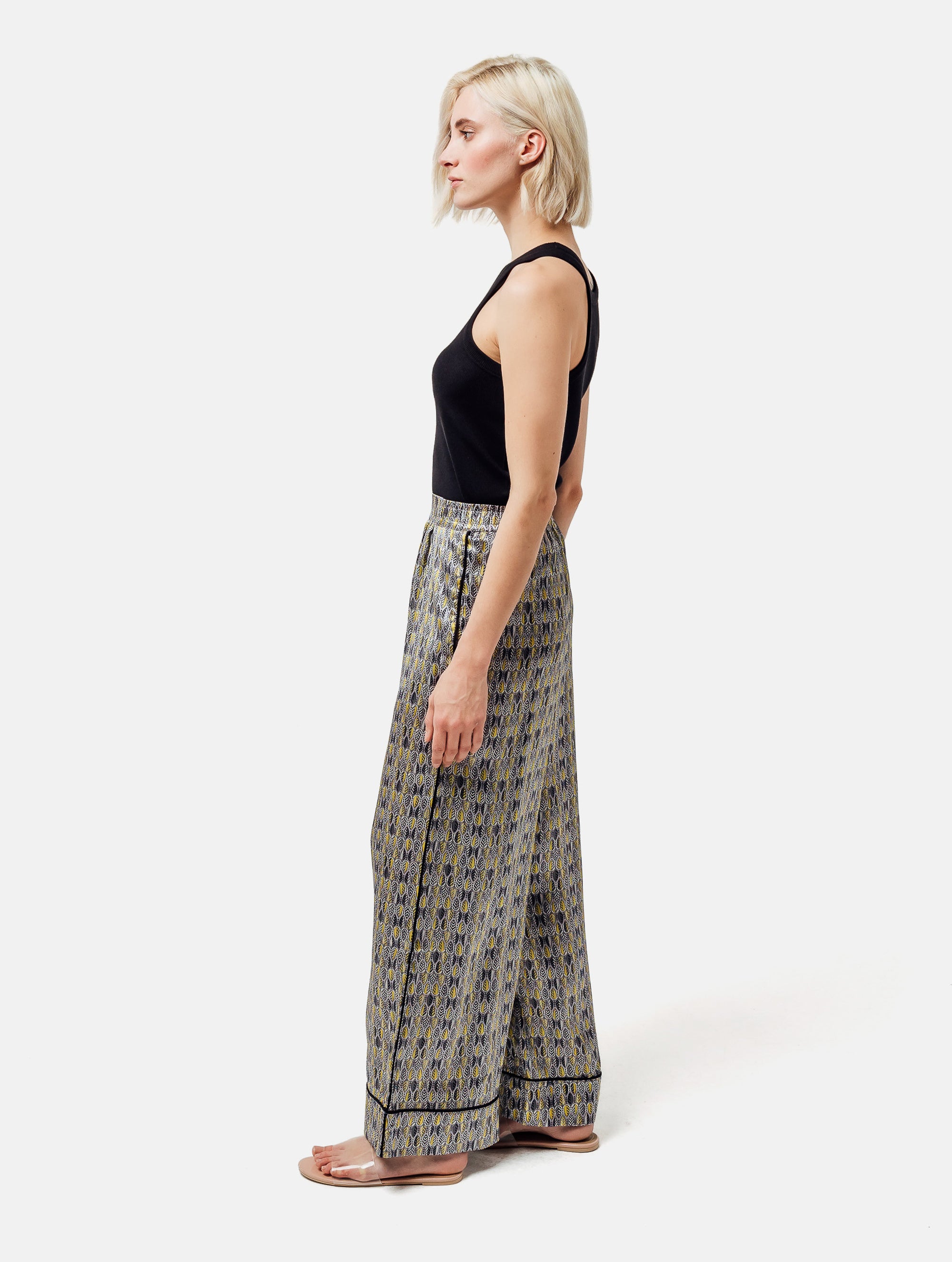 Bedruckte Satin-Seidenhose mit weitem Bein im Pyjama-Stil, elastischem Bund, Seitentaschen und schwarzen Paspeln. Hergestellt aus Naturfaser.