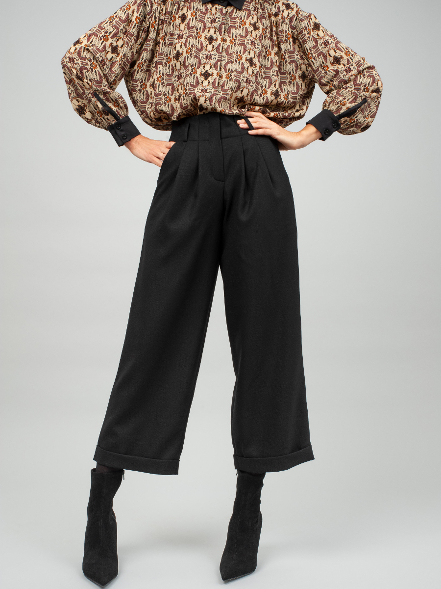 Schwarze Woll-Culotte mit hohem Bund Bundfalten, seitlichen Taschen und kleinen Aufschlägen am Hosenbein