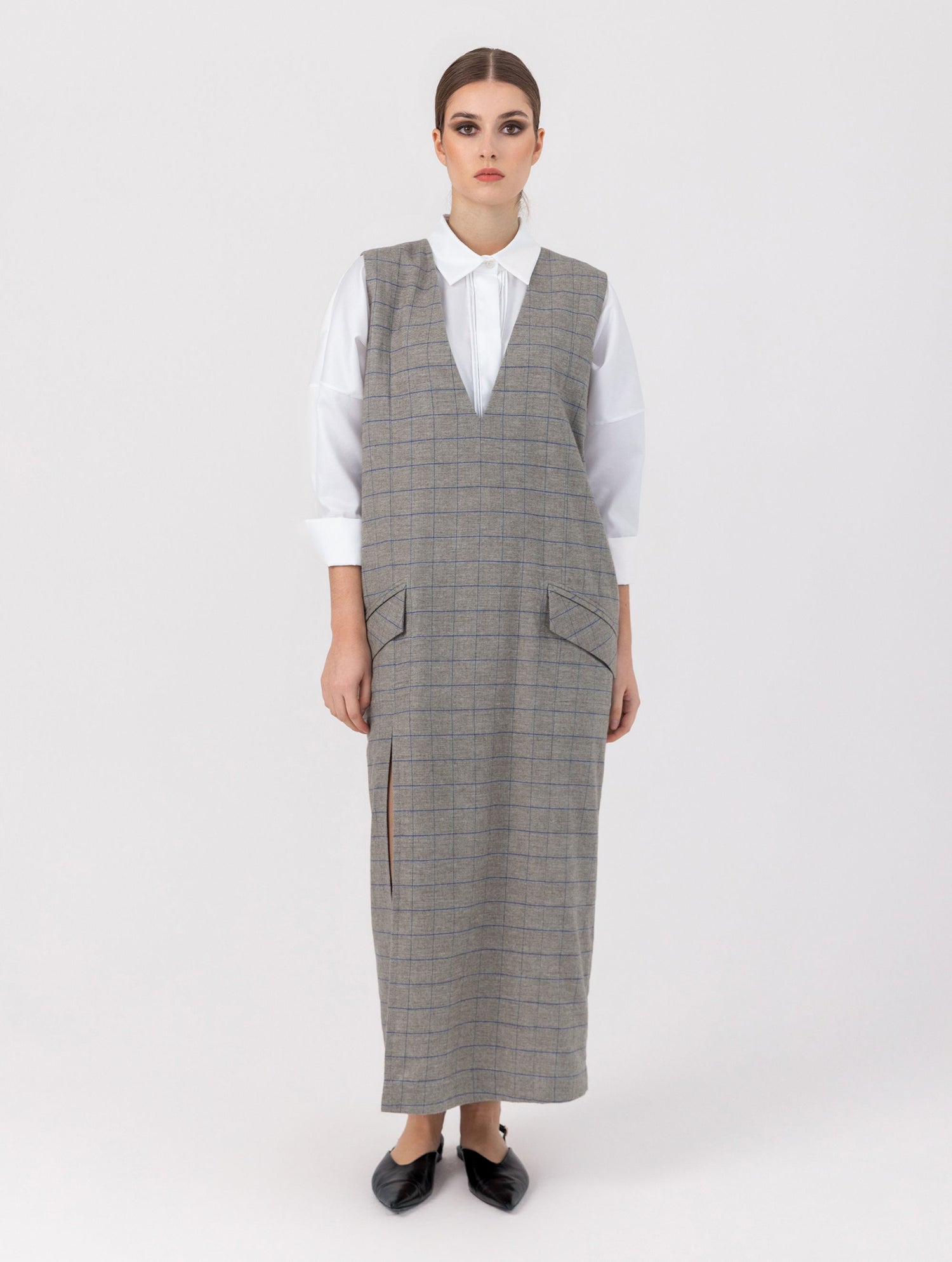 Ärmelloses, locker geschnittenes Kleid mit tiefem V-Ausschnitt und Pattentaschen sowie einem langen Seitenschlitz auf der Vorderseite. Hergestellt aus nachhaltigen Fasern.