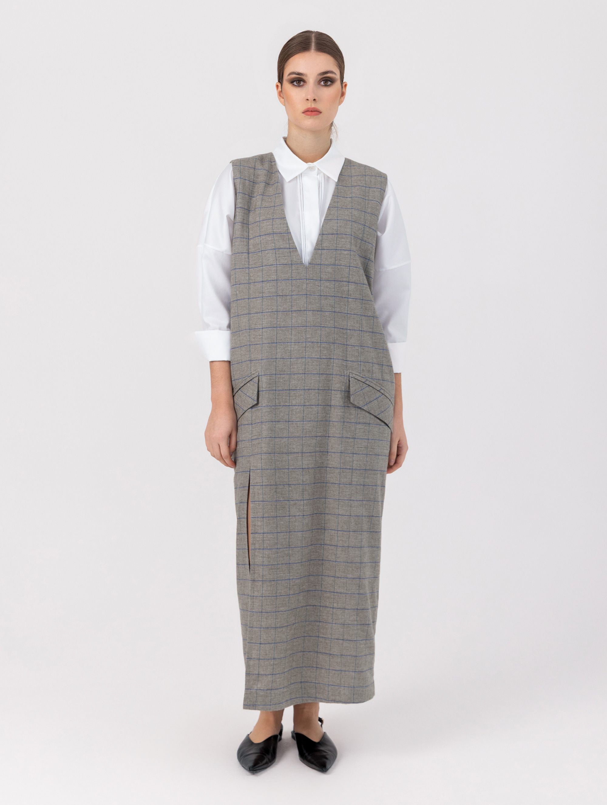 Ärmelloses, locker geschnittenes Kleid mit tiefem V-Ausschnitt und Pattentaschen sowie einem langen Seitenschlitz auf der Vorderseite. Hergestellt aus nachhaltigen Fasern.