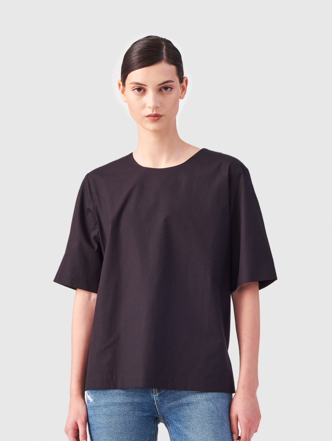 Hochgeschlossene Bluse aus Baumwolle im T-Shirt-Stil mit Knopfverschluss auf der Rückseite.