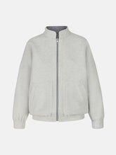 Wendbare Blousonjacke aus hochwertiger Merinowolle mit Stehkragen, Bündchen an den Ärmelenden und am Saumende, sowie seitlichen Leistentaschen auf der helleren Seite und großen aufgesetzten Taschen auf der dunkleren Seite. Dieses Modell ist Teil unserer REBORN-Linie und steht für unsere "Zero-Waste-Politik", da mit Stoff aus Altbestand gefertigt.