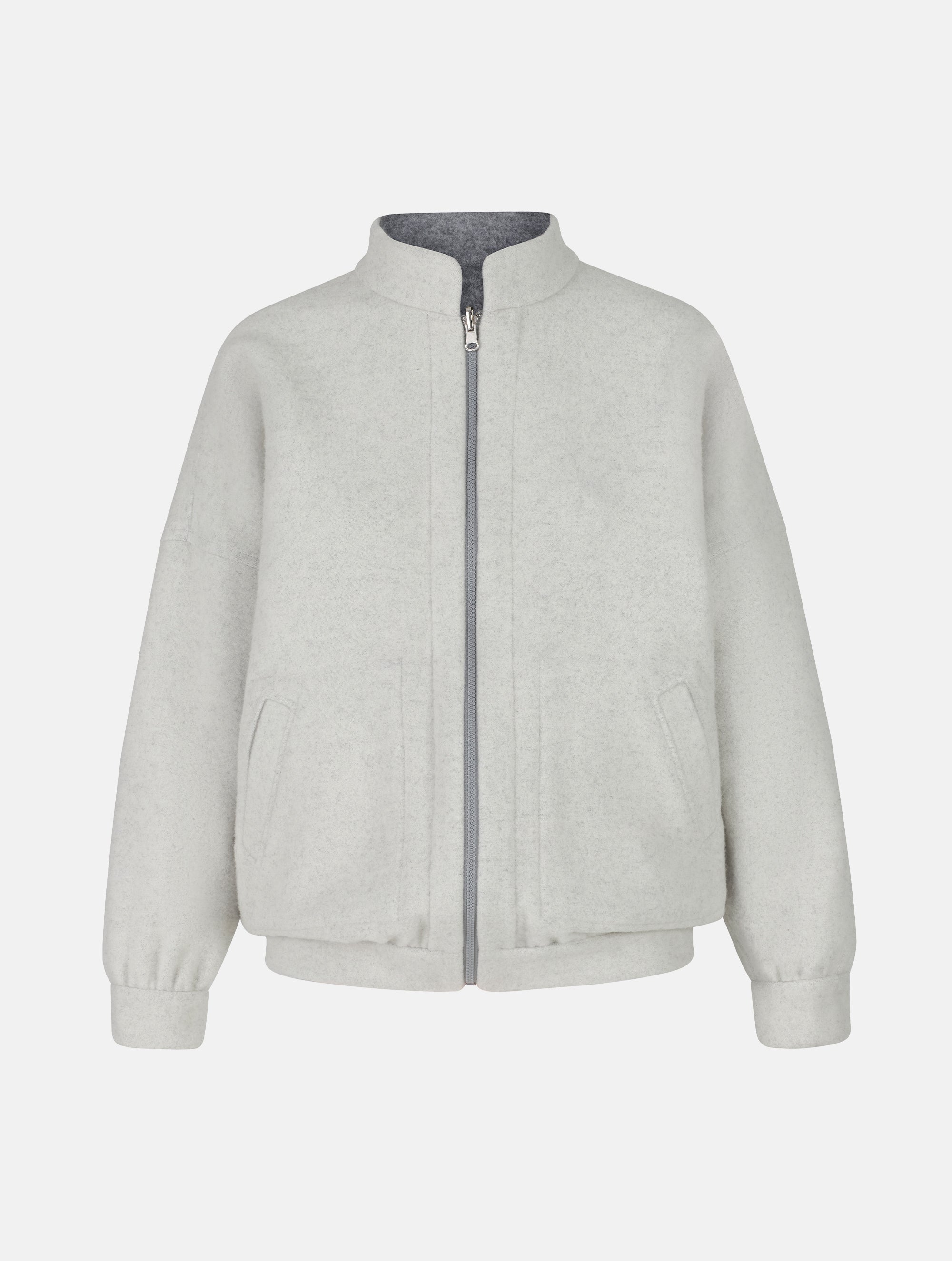Wendbare Blousonjacke aus hochwertiger Merinowolle mit Stehkragen, Bündchen an den Ärmelenden und am Saumende, sowie seitlichen Leistentaschen auf der helleren Seite und großen aufgesetzten Taschen auf der dunkleren Seite. Dieses Modell ist Teil unserer REBORN-Linie und steht für unsere "Zero-Waste-Politik", da mit Stoff aus Altbestand gefertigt.