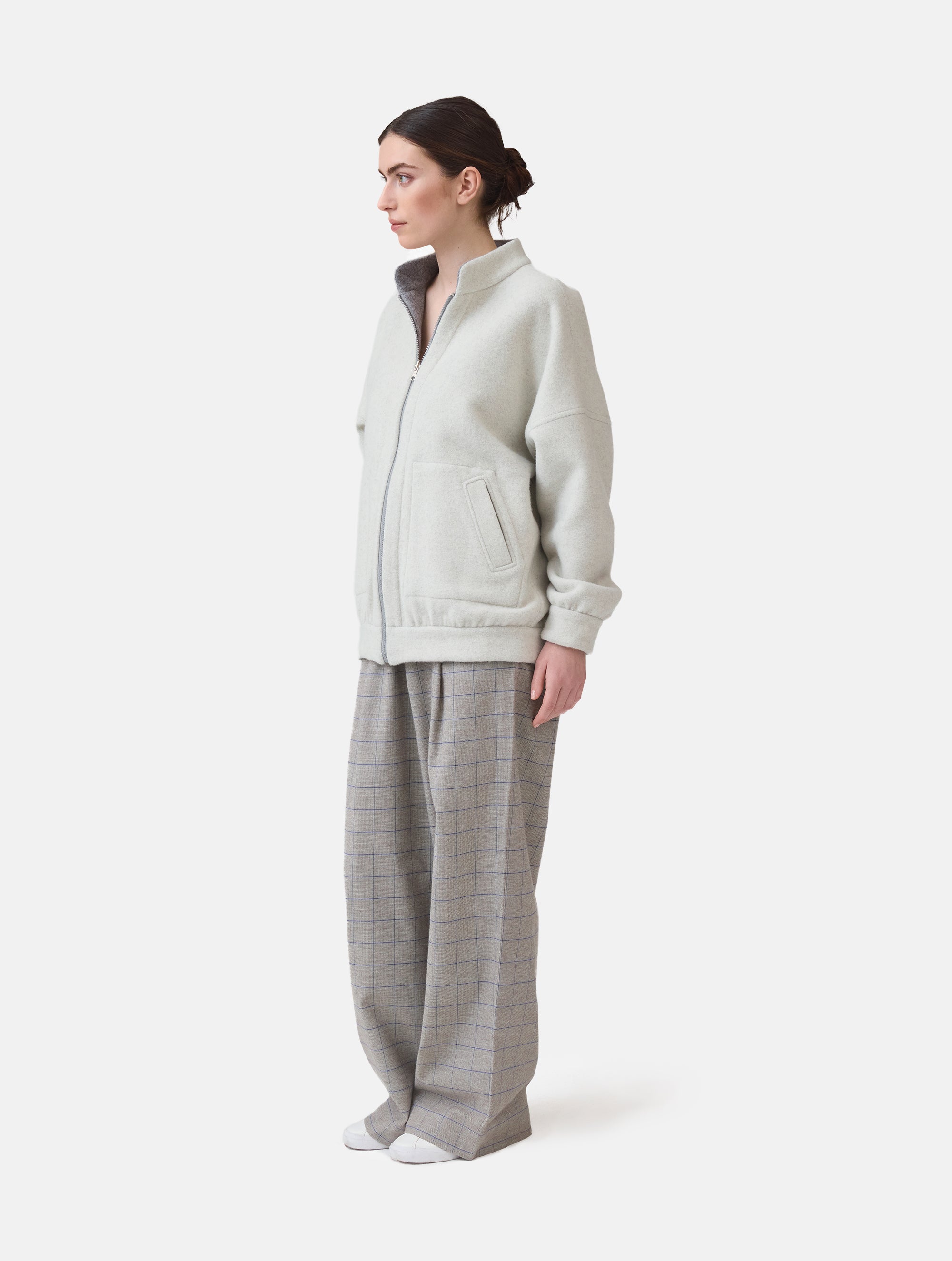Wendbare Blousonjacke aus hochwertiger Merinowolle mit Stehkragen, Bündchen an den Ärmelenden und am Saumende, sowie seitlichen Leistentaschen auf der helleren Seite und großen aufgesetzten Taschen auf der dunkleren Seite. Dieses Modell ist Teil unserer REBORN-Linie und steht für unsere "Zero-Waste-Politik", da mit Stoff aus Altbestand gefertigt.
