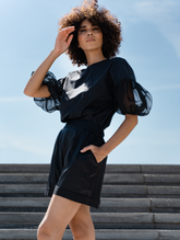 Schwarze Bluse mit Rundhalsausschnitt, Organza-Ärmeln, Seitenschlitzen und versteckten Seitentaschen