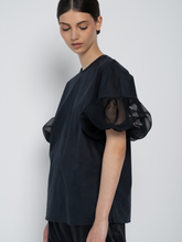 Schwarze Bluse mit Rundhalsausschnitt, Organza-Ärmeln, Seitenschlitzen und versteckten Seitentaschen