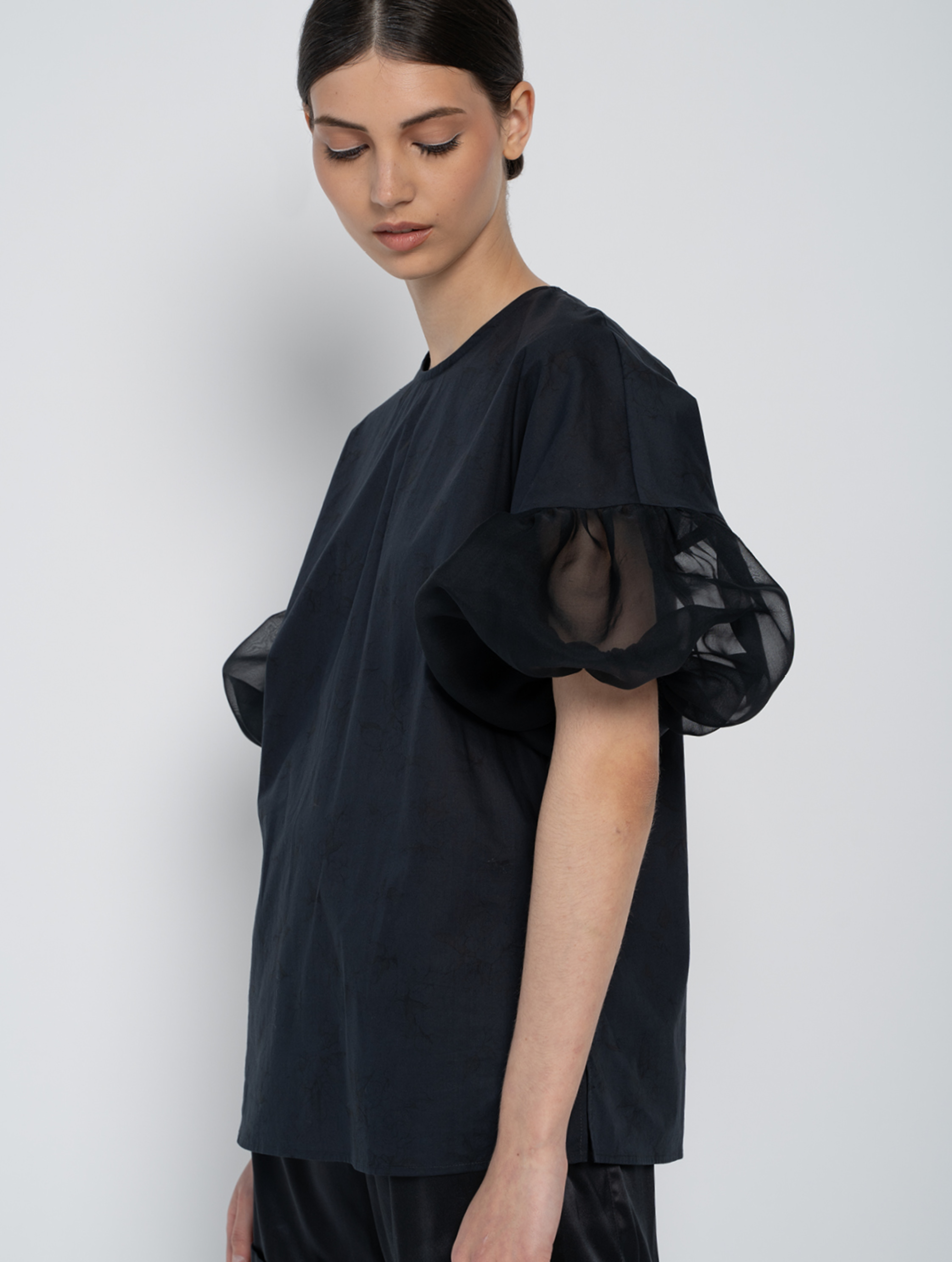 Schwarze Bluse mit Rundhalsausschnitt, Organza-Ärmeln, Seitenschlitzen und versteckten Seitentaschen