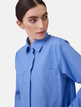 Langes Oversize Blusenhemd mit klassischem Hemdkragen und Manschetten, sowie zwei aufgesetzten Brutstaschen und abgerundeten Saumende im Rückteil.  Dieses Modell ist Teil unserer REBORN-Linie und steht für unsere "Zero-Waste-Politik", da mit Stoff aus Altbestand gefertigt.