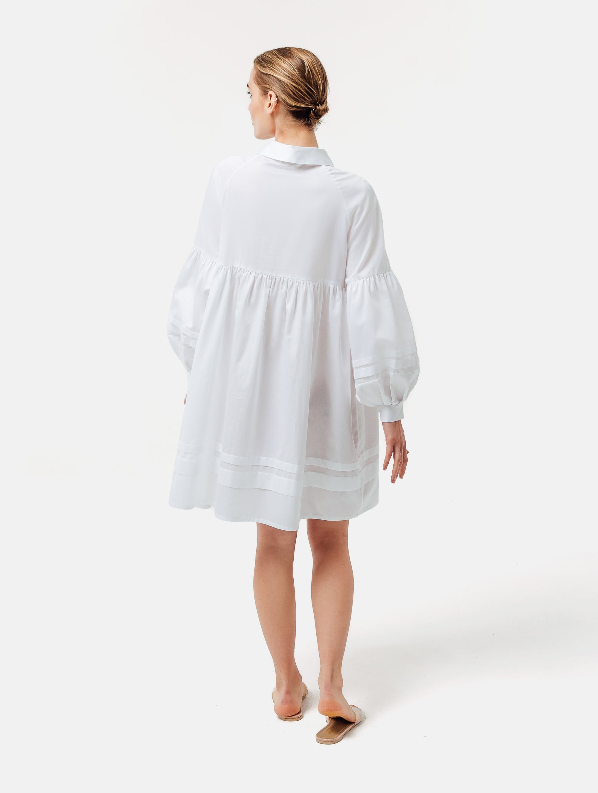 Weites Hemdkragenkleid mit weiten Laternenärmeln, Biesen an der Brust, Ärmeln, aufgesetzenTaschen und Saumende, sowie verdeckter Knopfleiste. Gefertigt aus Premiumbaumwolle mit Satin-Touch.