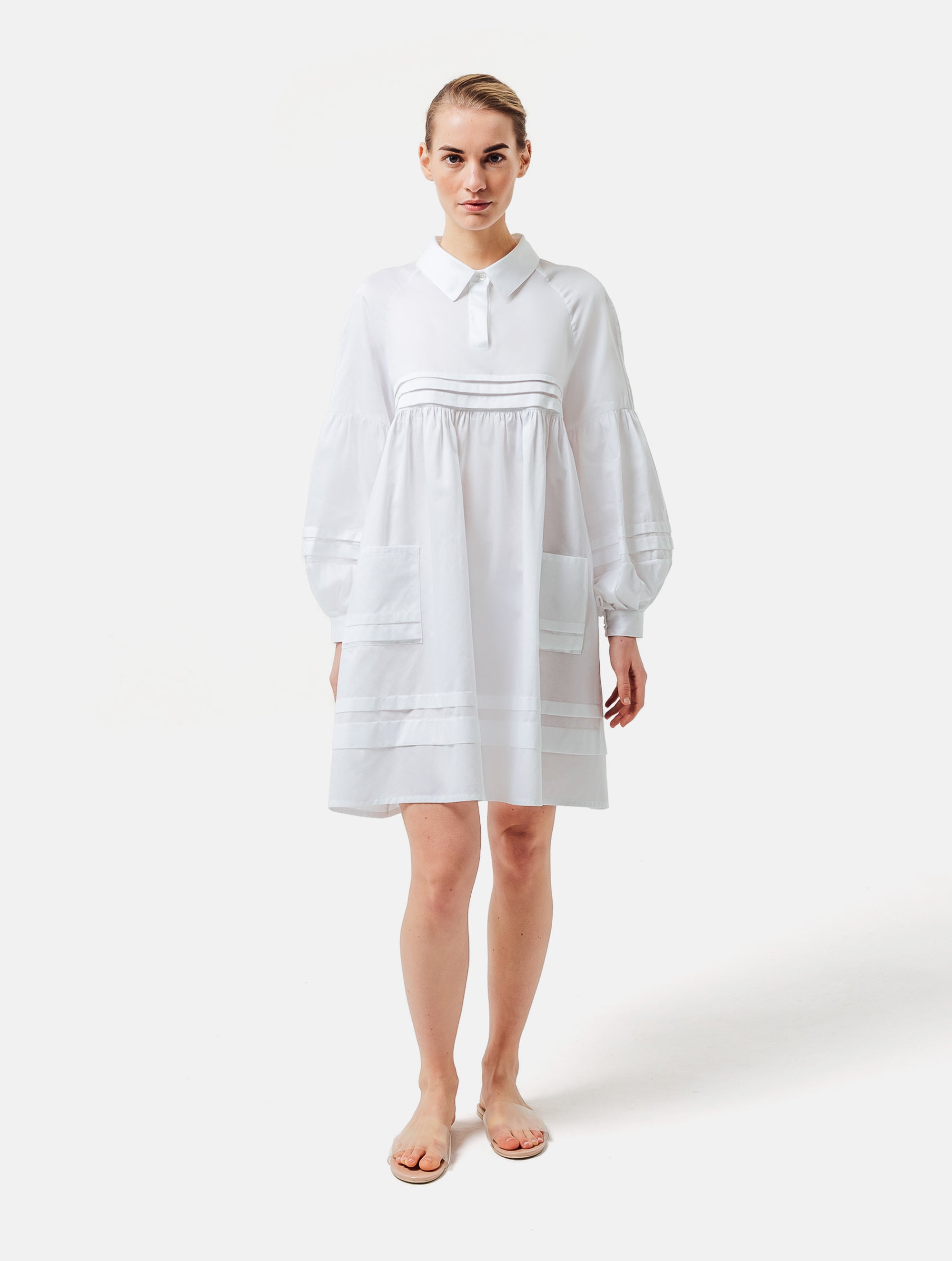 Weites Hemdkragenkleid mit weiten Laternenärmeln, Biesen an der Brust, Ärmeln, aufgesetzenTaschen und Saumende, sowie verdeckter Knopfleiste. Gefertigt aus Premiumbaumwolle mit Satin-Touch.