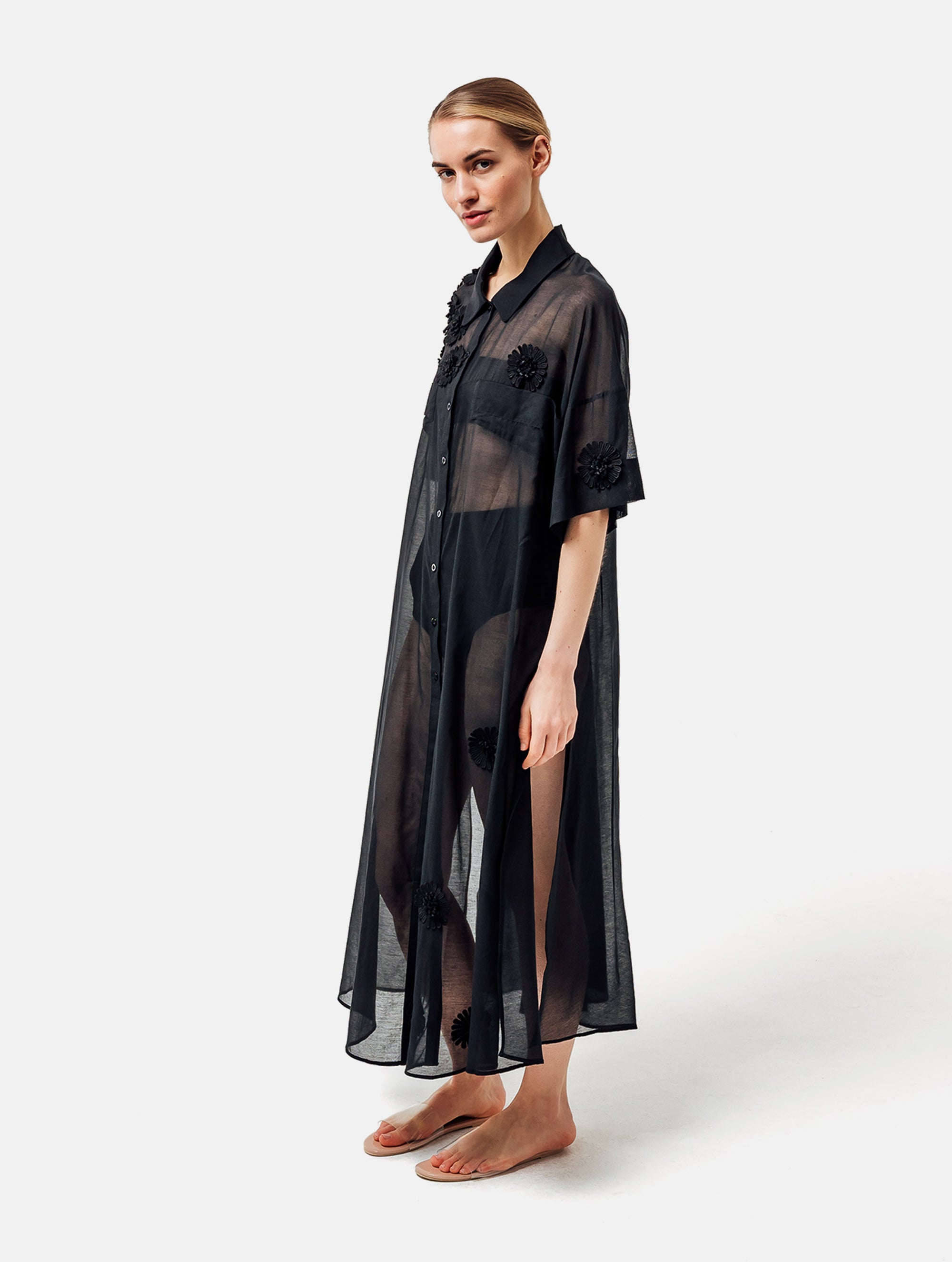 Ultraleichtes Kaftankleid mit Blumenapplikationen, Hemdkragen und langer Knopfleiste vorne, hohen Seitenschlitzen, sowie großen Brusttaschen. Dieses Produkt ist Teil unserer Reborn Linie.