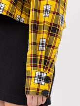 Doppelseitige Karo-Kurzjacke mit abnehmbaren Schulterpolstern, eingesetzten Ärmeln mit Ärmelgürteln und Schulterklappen sowie vorderen Halbpasse. Die Jacke kann von beiden Seiten getragen werden.   Hergestellt aus Naturfasern. 