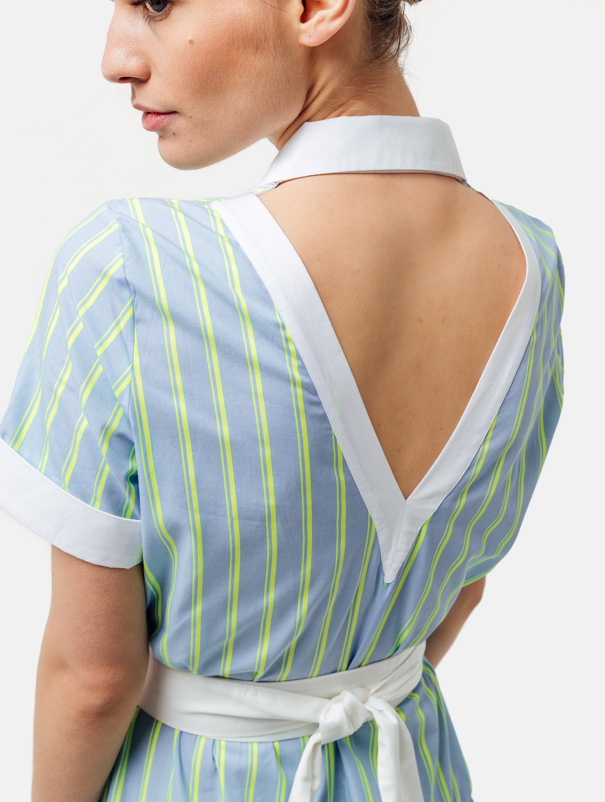Gestreiftes Midikleid mit weiß abgesetzten Reverskragen, sowie Ärmelenden, raffiniertem Rückenausschnitt, verdeckter Knopfleiste, tragbar mit und ohne Gürtel aus weißer Baumwolle. Stoffe kommen aus dem Altbestand der Firma, daher nachhaltig.