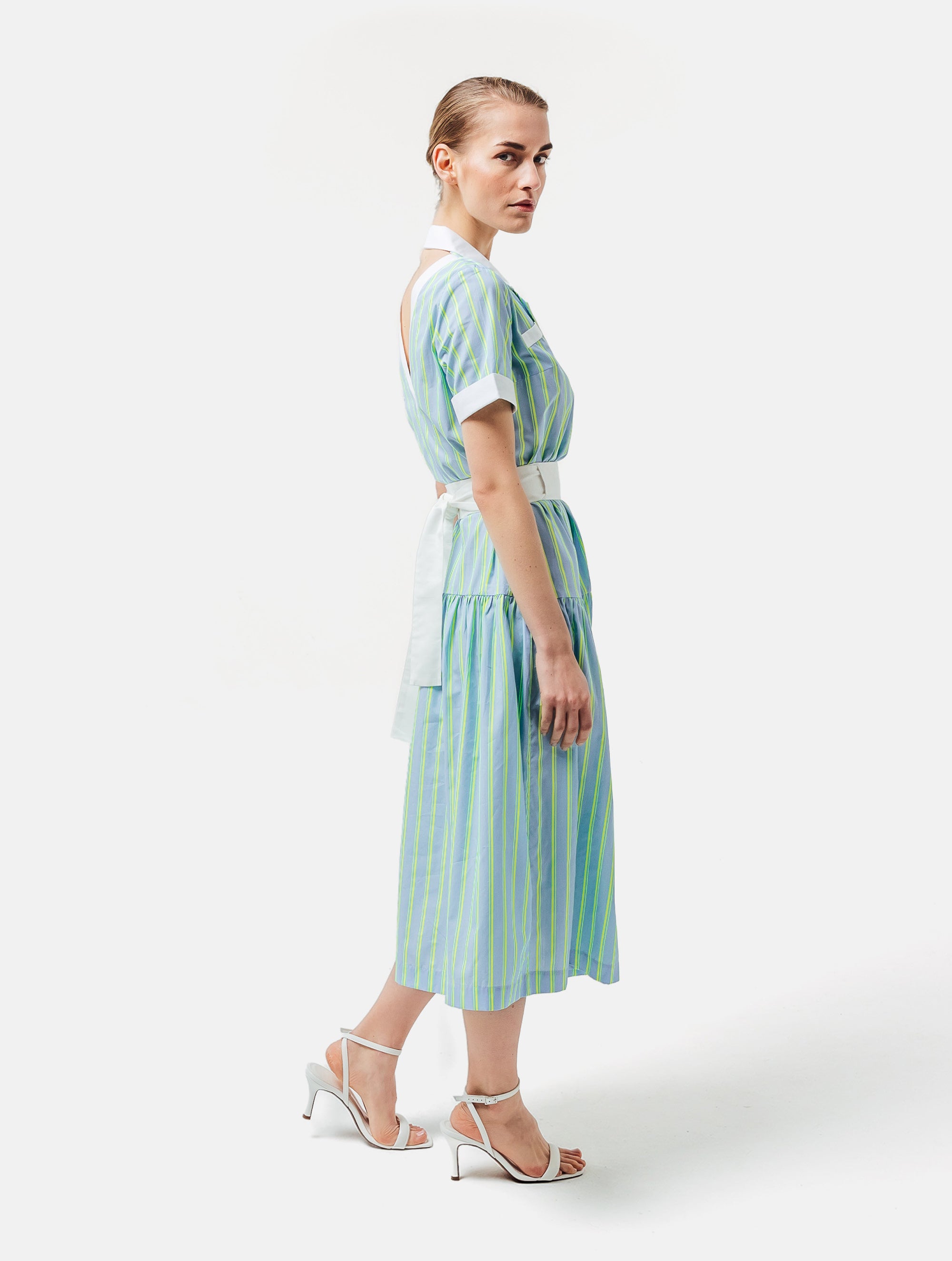 Gestreiftes Midikleid mit weiß abgesetzten Reverskragen, sowie Ärmelenden, raffiniertem Rückenausschnitt, verdeckter Knopfleiste, tragbar mit und ohne Gürtel aus weißer Baumwolle. Stoffe kommen aus dem Altbestand der Firma, daher nachhaltig.