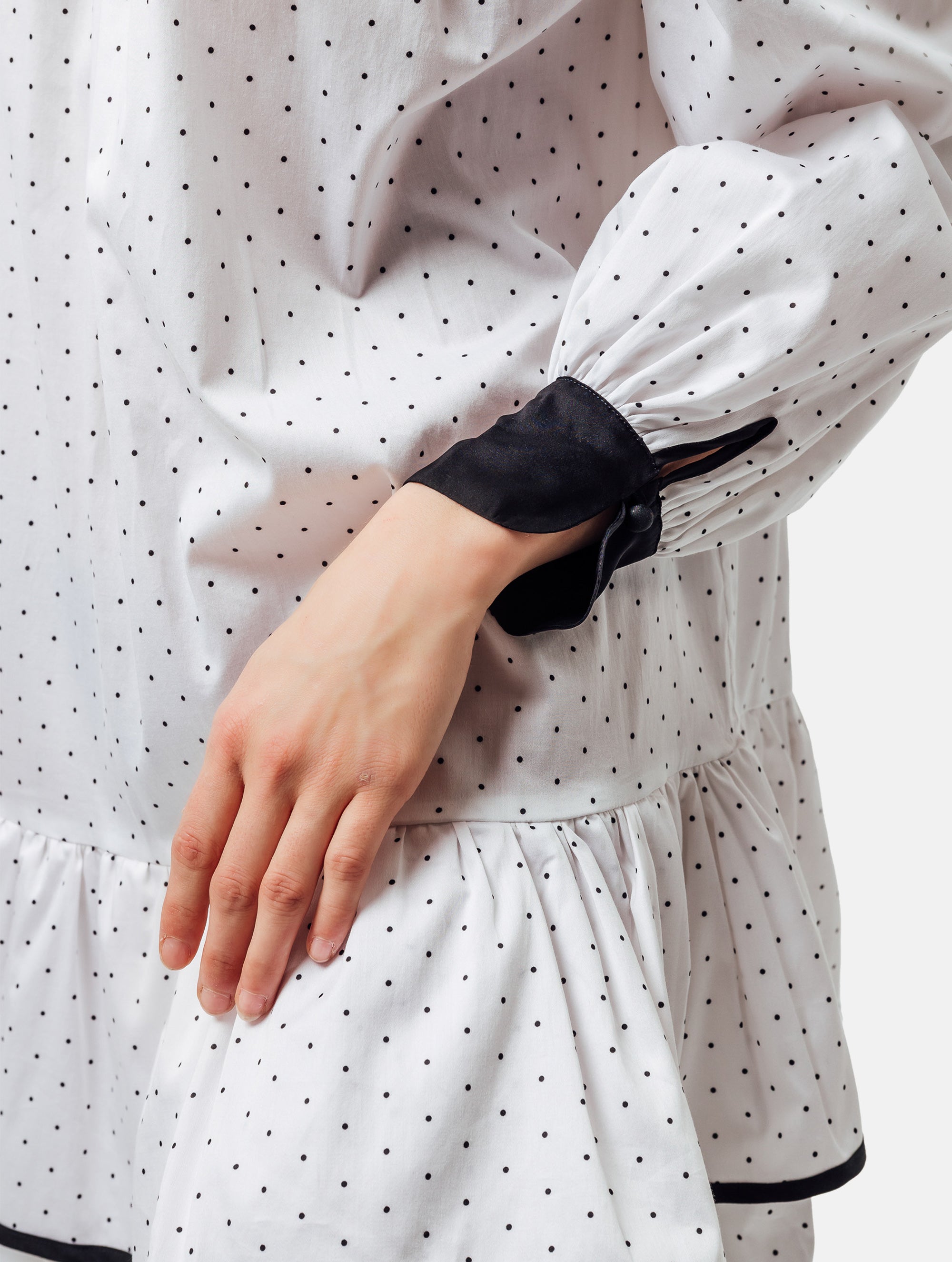 Grade geschnittenes Minikleid aus gepunkteter Baumwolle mit farblich abgesetzten Kragen und Manschetten aus schwarzer Chiffonseide, sowie doppelten Volantssaum. 