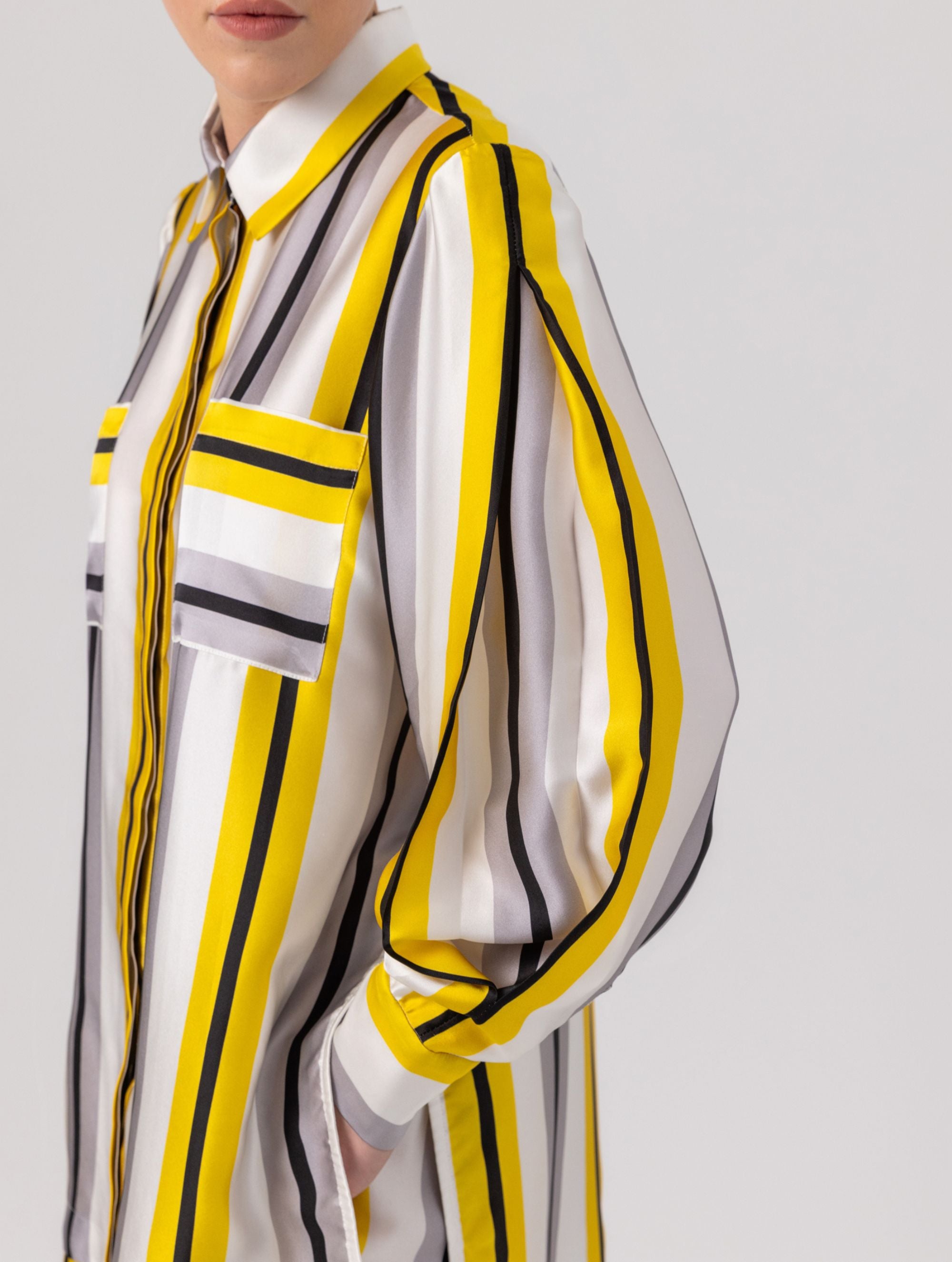 Bedruckte Oversize-Seidenbluse aus Satin mit Hemdkragen, aufgesetzten Taschen auf der Vorderseite und Kellerfalte auf der Rückseite sowie schwarzem Chiffonschal.  Hergestellt aus Naturfasern, sowie Stoffen aus unserem Altbestand im Sinne unserer "Zero-Waste-Politik".