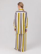 Bedruckte Oversize-Seidenbluse aus Satin mit Hemdkragen, aufgesetzten Taschen auf der Vorderseite und Kellerfalte auf der Rückseite sowie schwarzem Chiffonschal.  Hergestellt aus Naturfasern, sowie Stoffen aus unserem Altbestand im Sinne unserer "Zero-Waste-Politik".