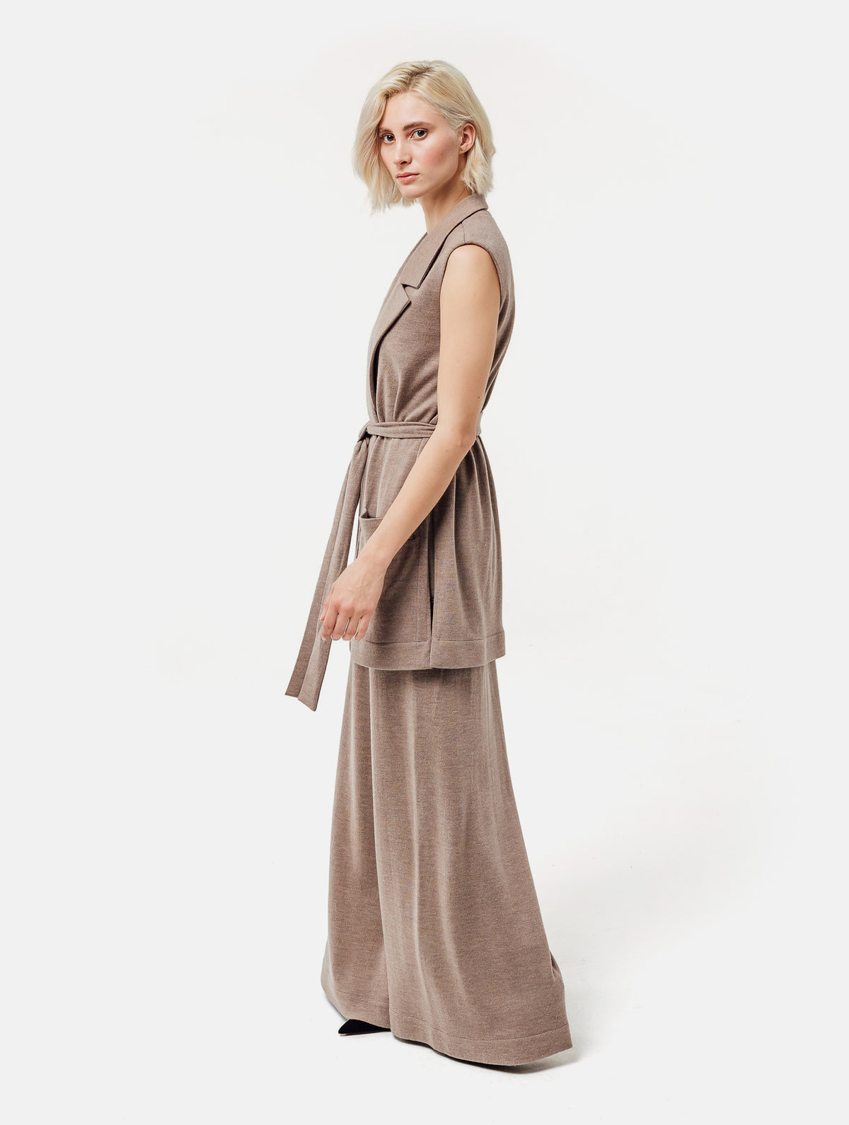 Strickweste mit versteckten Druckknöpfen und passendem Strickgürtel, großzügigen Reverskragen und großen integrierten Taschen, sowie Seitenschlitzen. Dieses Modell ist Teil unserer REBORN-Linie und steht für unsere "Zero-Waste-Politik", da mit Stoff aus Altbestand gefertigt.