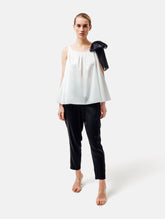 Weit geschnittenes Tanktop aus weißer Baumwolle mit schwarzem Schleifendetail und seperaten Gürtel aus schwarzer Baumwolle. Versteckte Seitentaschen in den Seitennähten. Dieses Produkt ist Teil unserer Reborn Linie.