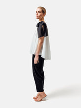 Weit geschnittenes Tanktop aus weißer Baumwolle mit schwarzem Schleifendetail und seperaten Gürtel aus schwarzer Baumwolle. Versteckte Seitentaschen in den Seitennähten. Dieses Produkt ist Teil unserer Reborn Linie.